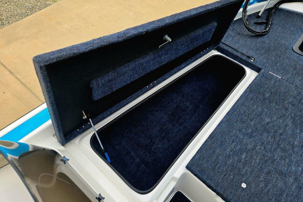 Open storage compartment on a 1996 Champion 181 SX boat, featuring blue carpet lining.