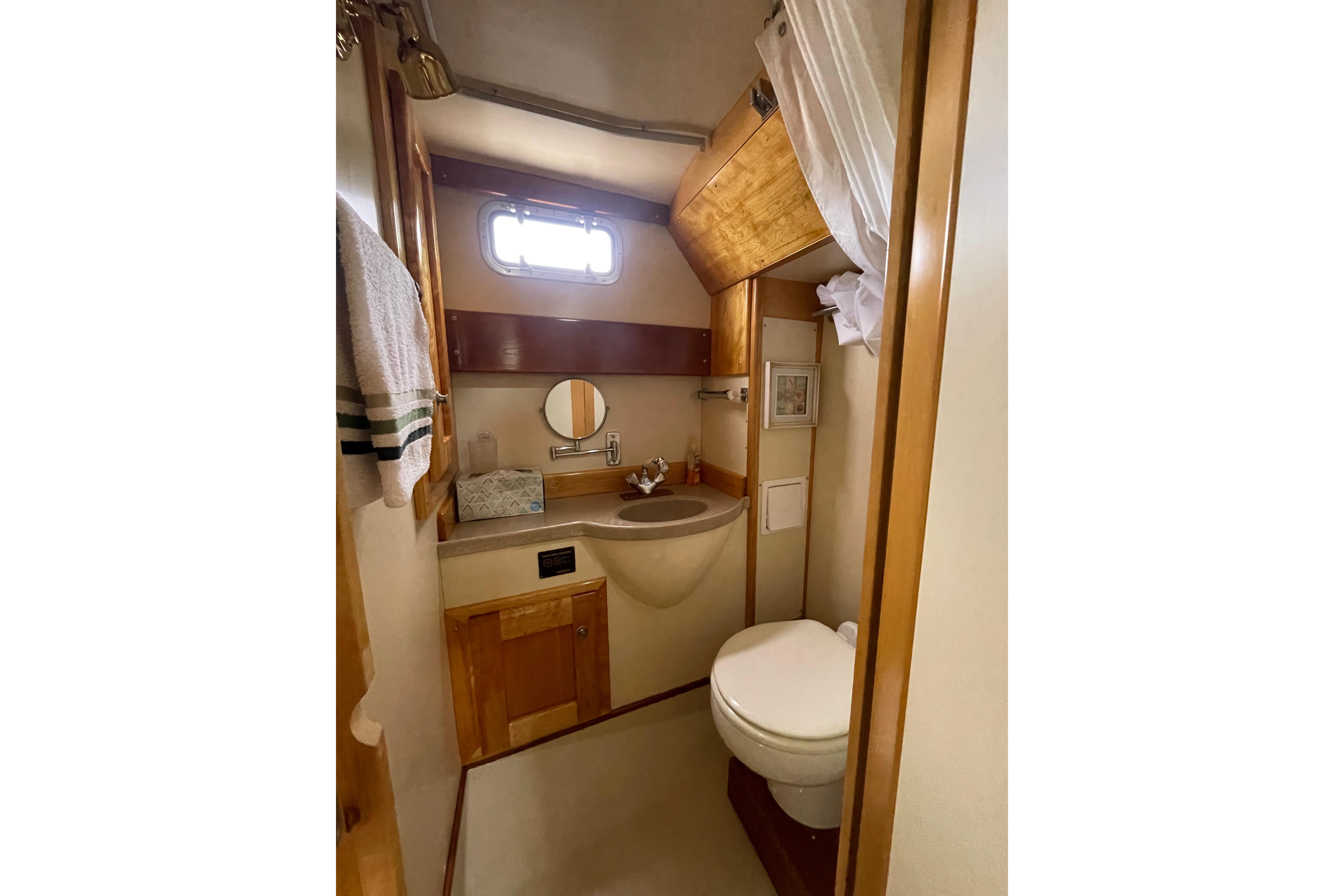 Bathroom interior of 2005 Fox Island Thirty Sedan Cruiser, featuring sink, toilet, and wooden cabinetry.