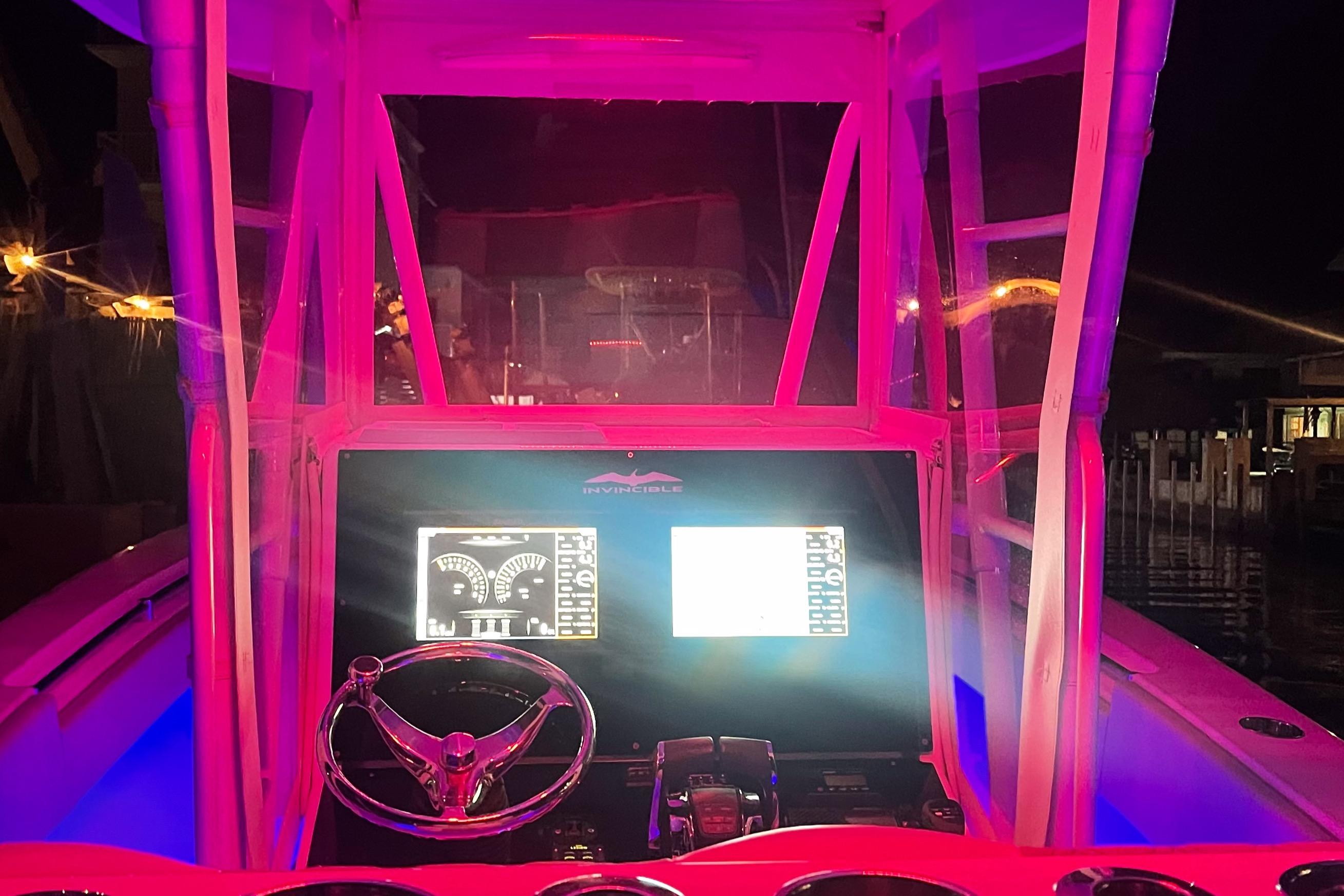 Cockpit of 2008 Invincible 33 boat illuminated with vibrant pink lighting at night.