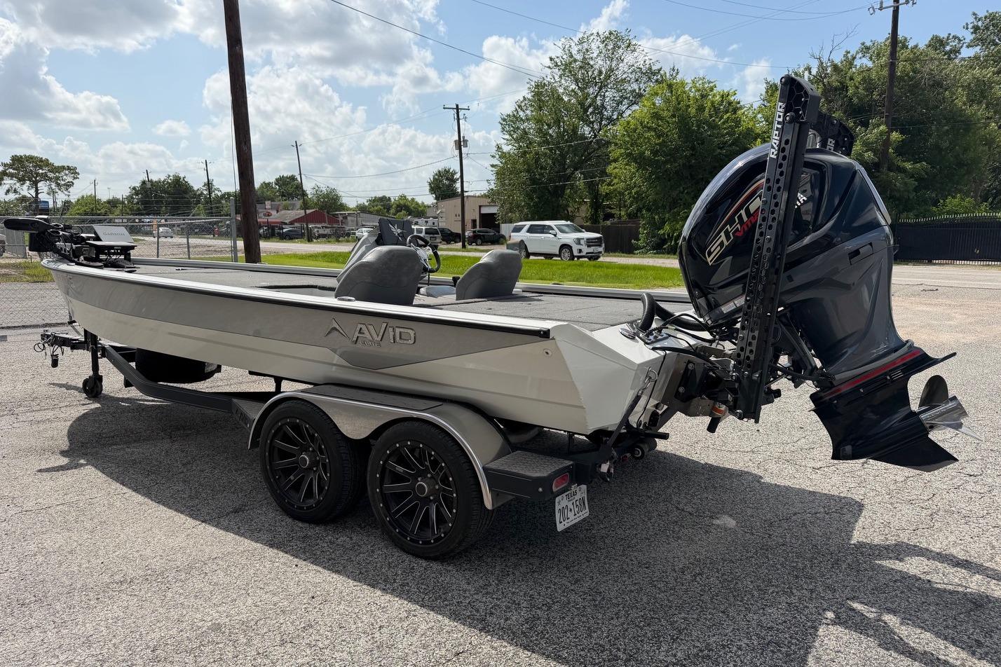 2024 Avid 21 XB Elite boat on trailer with powerful outboard motor, parked outdoors.