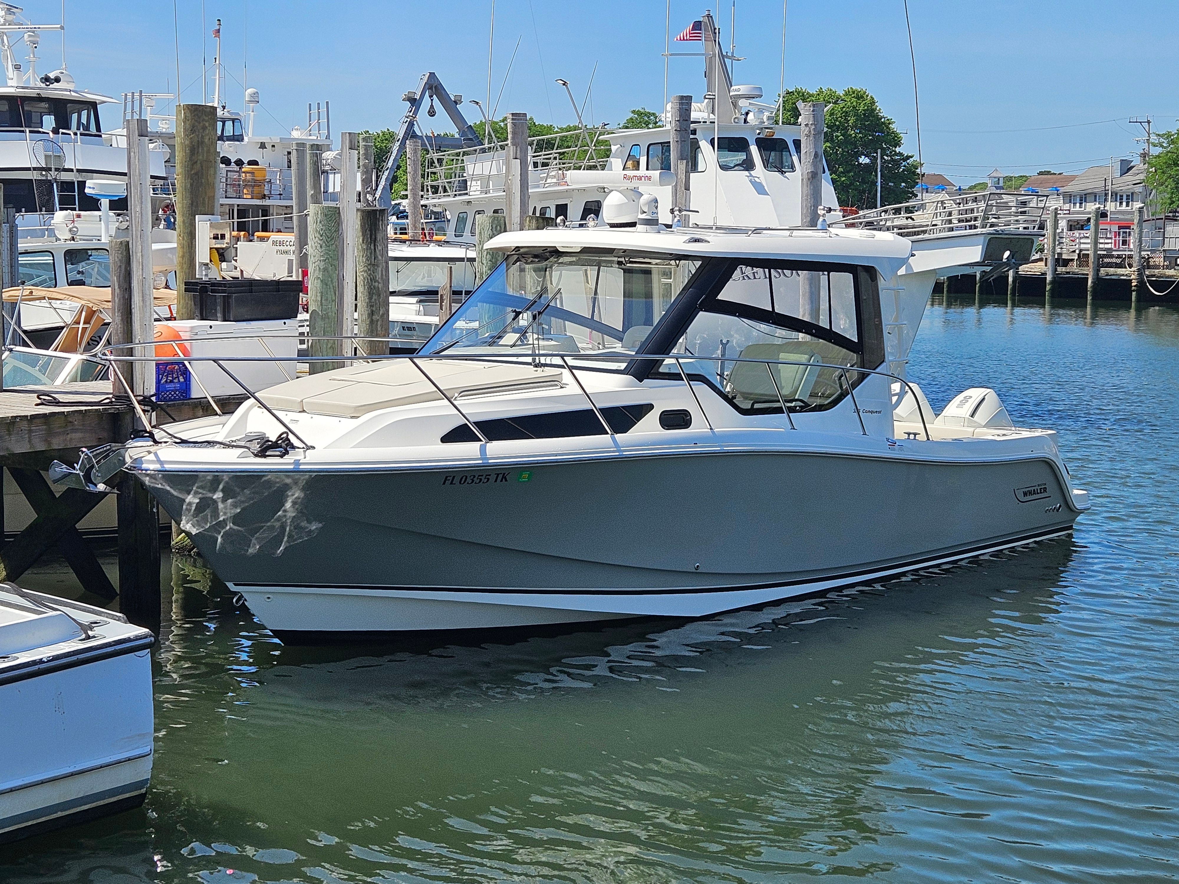 A 2023 Boston Whaler 325 Conquest docked in a harbor setting.