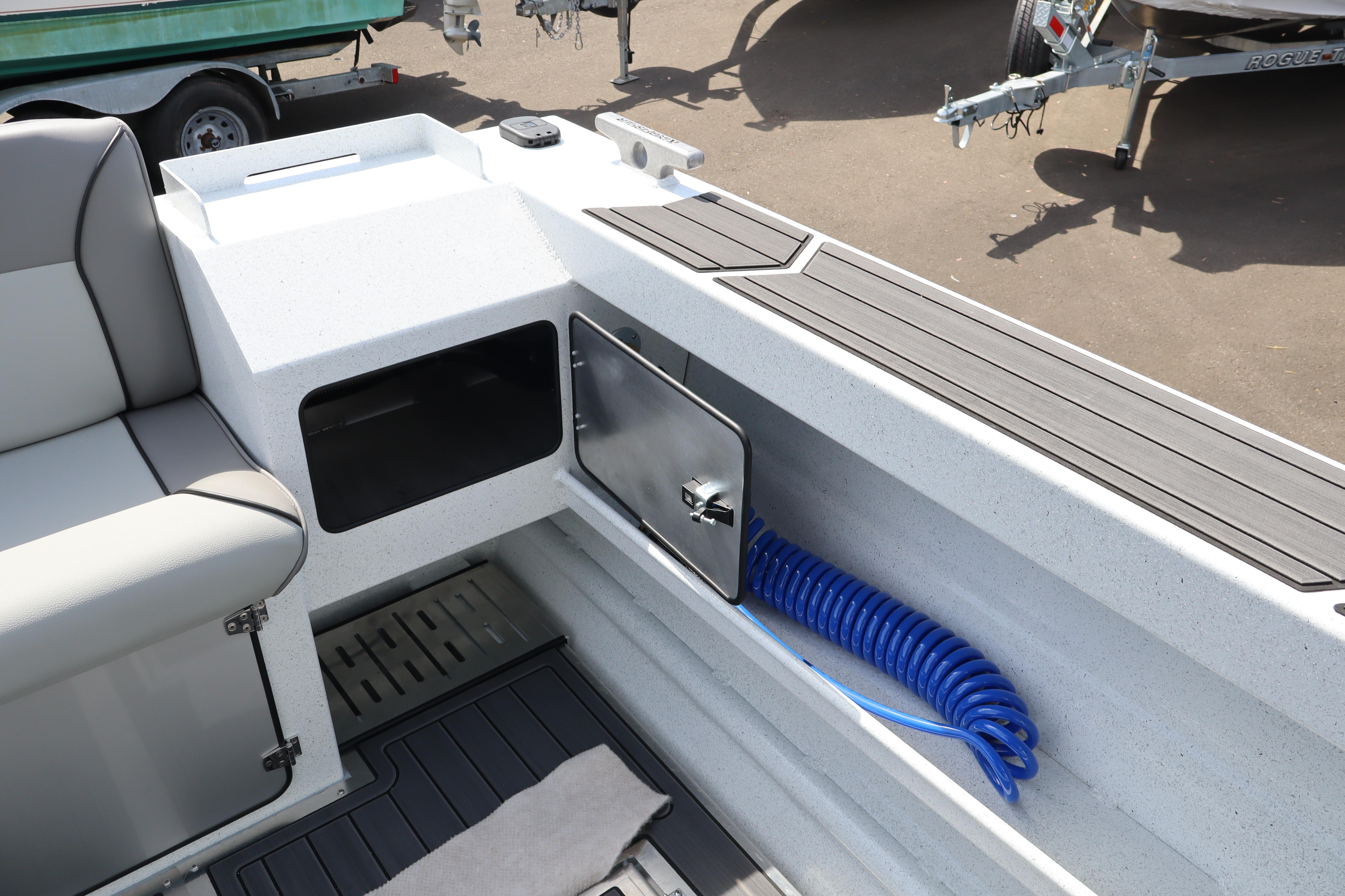 Interior of 2026 KingFisher 25 XAC boat with storage compartment and coiled blue hose.