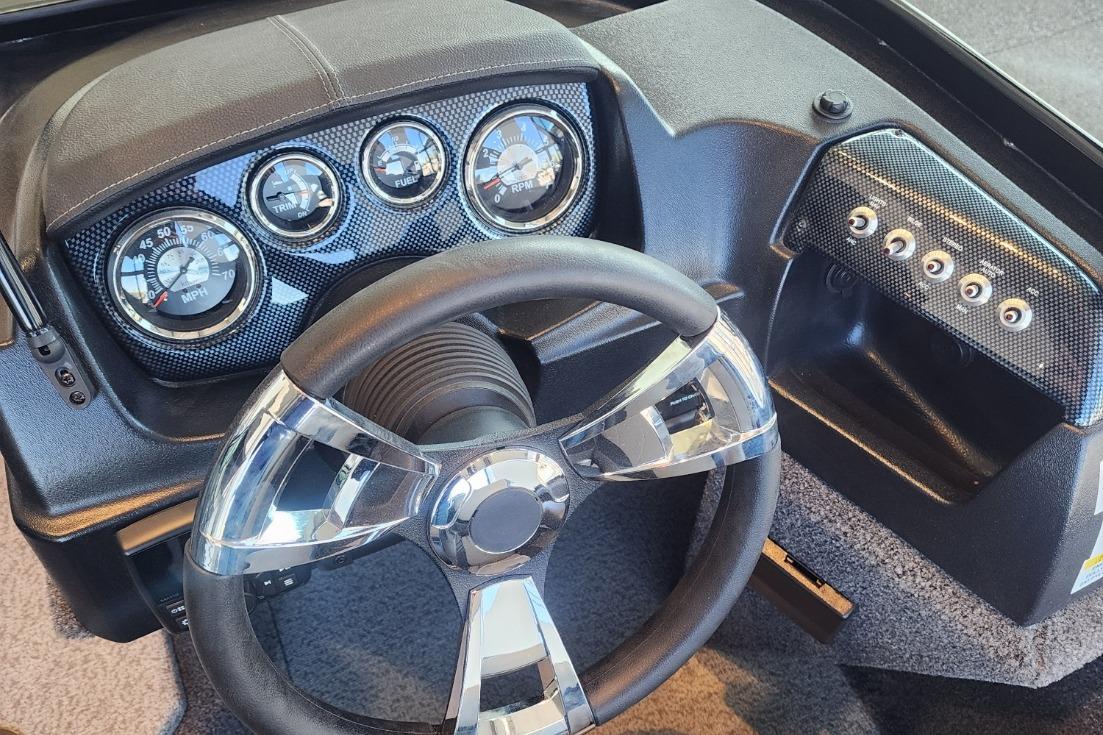 Steering wheel and dashboard of a 2023 Lowe boat with gauges and controls.