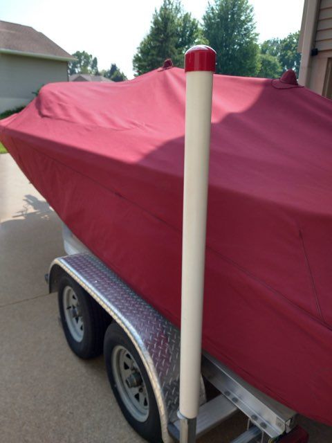 A 2006 Chris-Craft Speedster 20 covered with a red tarp, sitting on a trailer.