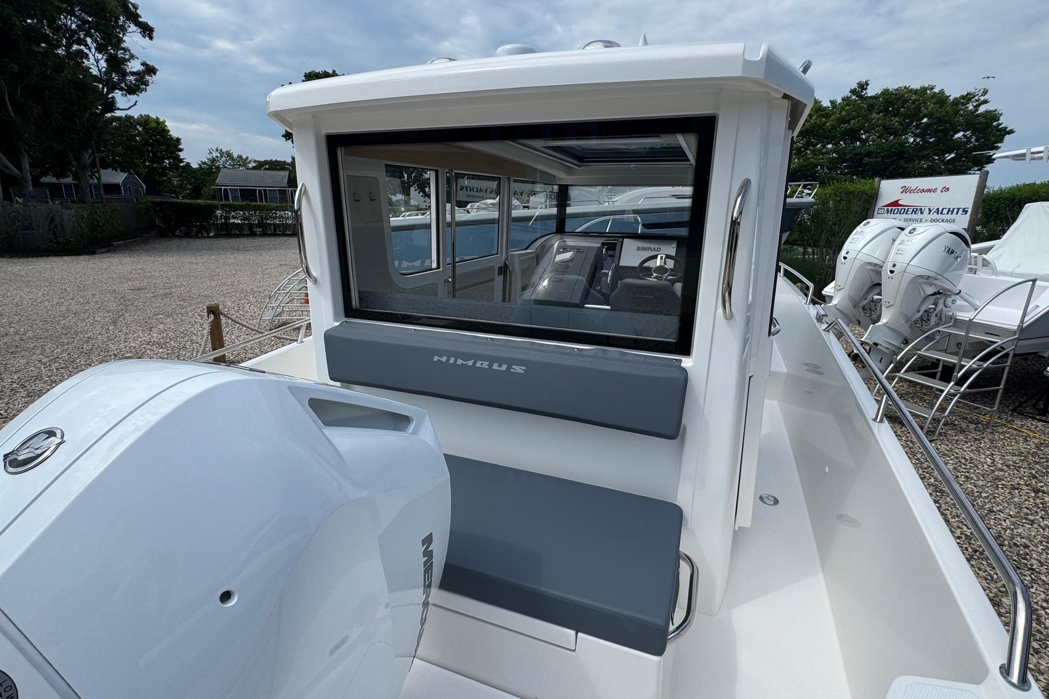 2026 Nimbus Commuter 9 with gray seating and outboard motor, parked at a marina.