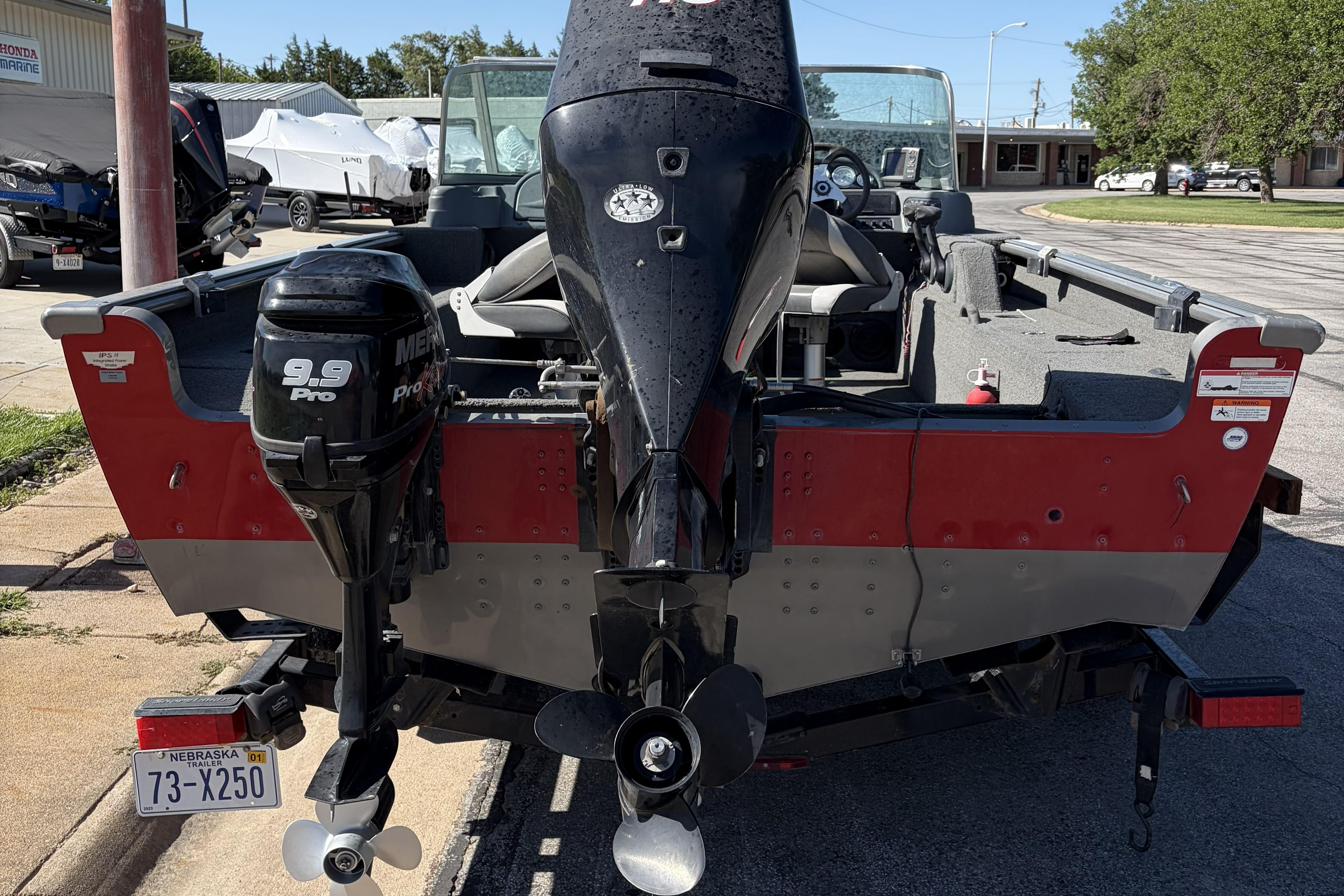 2010 Lund 1825 Explorer boat with Mercury 9.9 Pro outboard motor, parked on a street.