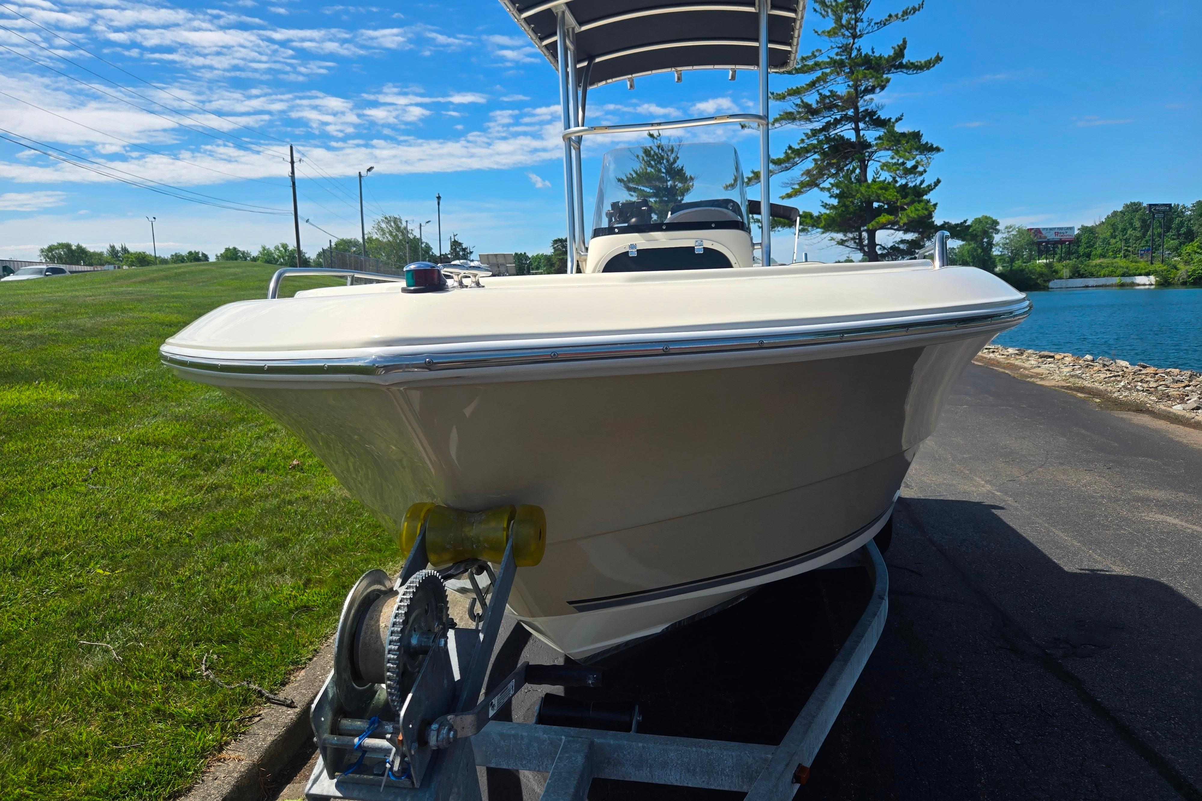 2016 Key Largo 2000CC boat on trailer by a lake under blue sky.