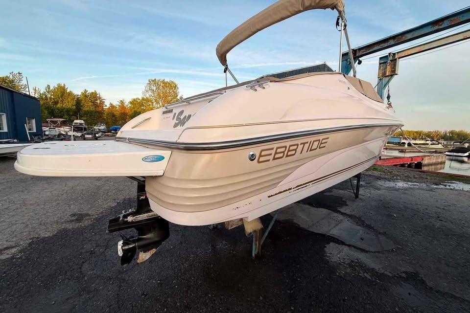 1999 Ebbtide 2300 Bow Rider boat on dry dock, showcasing sleek design and branding.