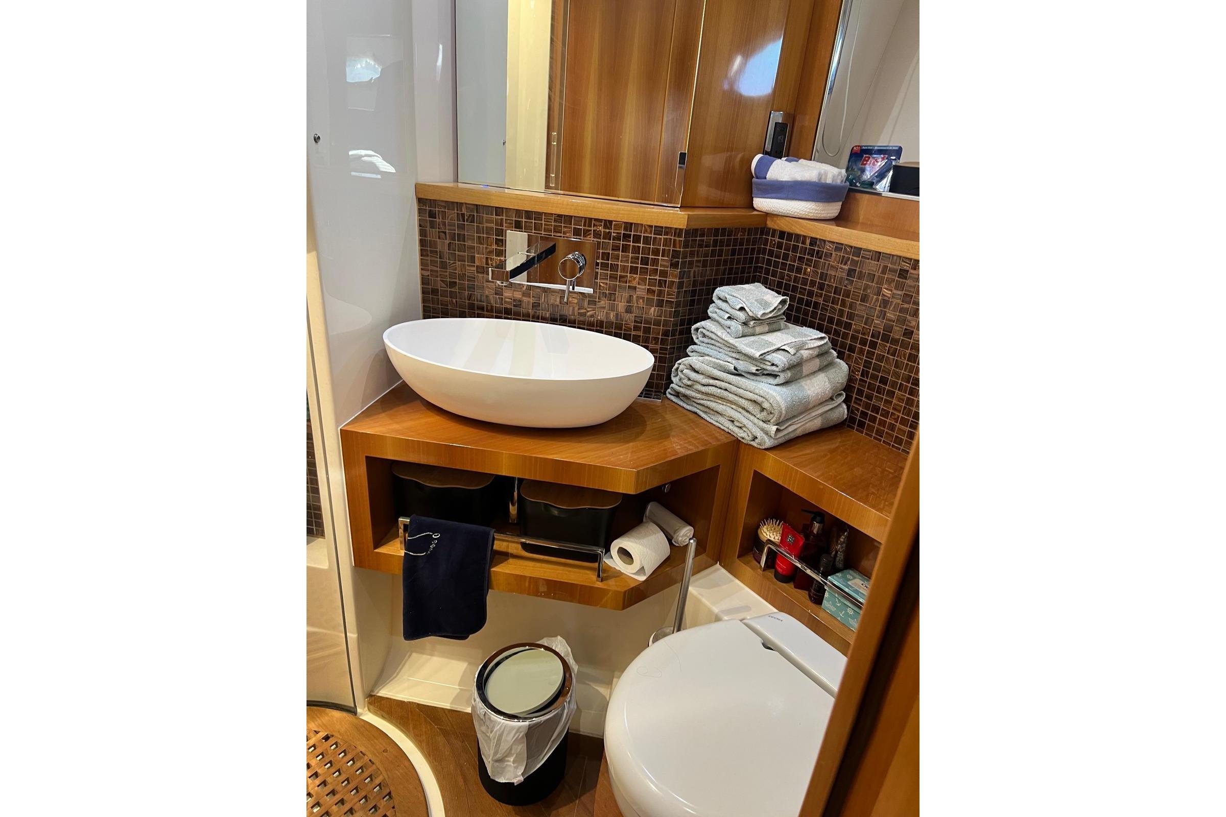 Luxurious yacht bathroom with modern sink, wooden cabinetry, and neatly stacked towels.