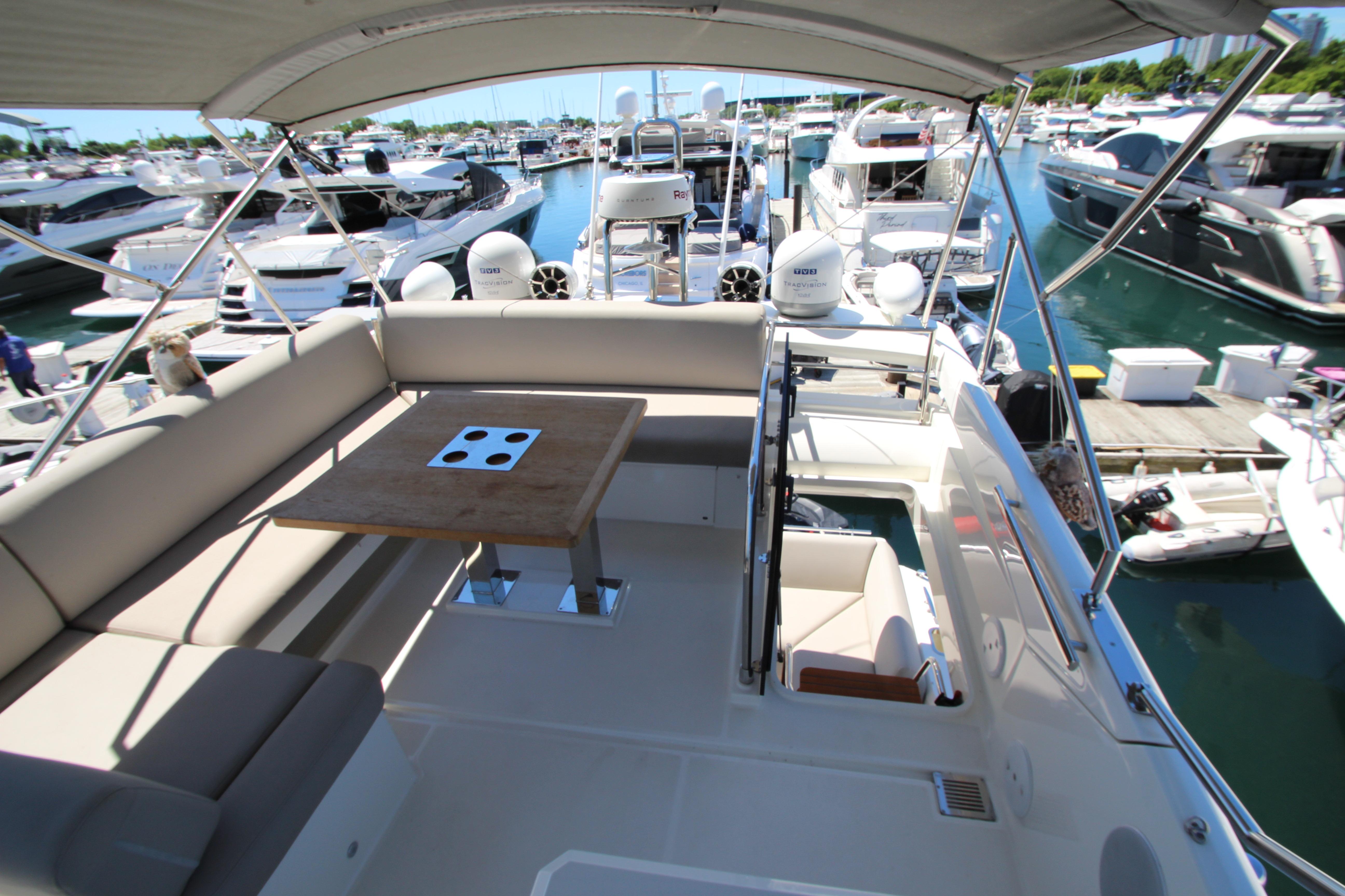 Luxurious 2022 Prestige 520 yacht interior with seating and table, docked at marina.