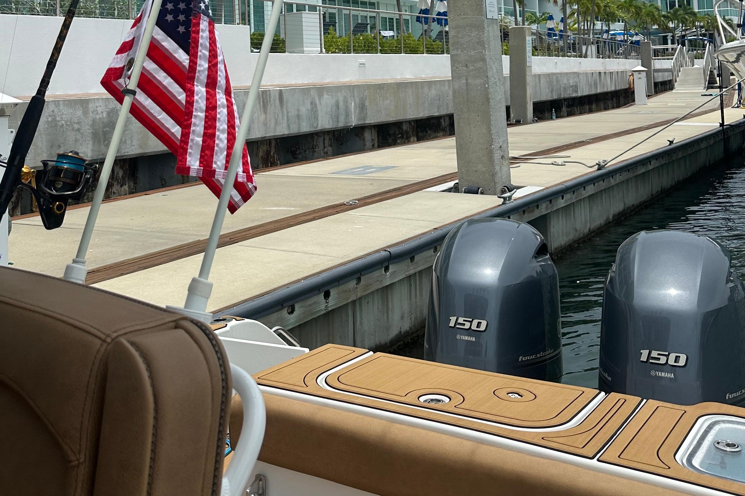 2019 Sea Hunt Gamefish 25 with twin Yamaha 150 engines docked, featuring an American flag.