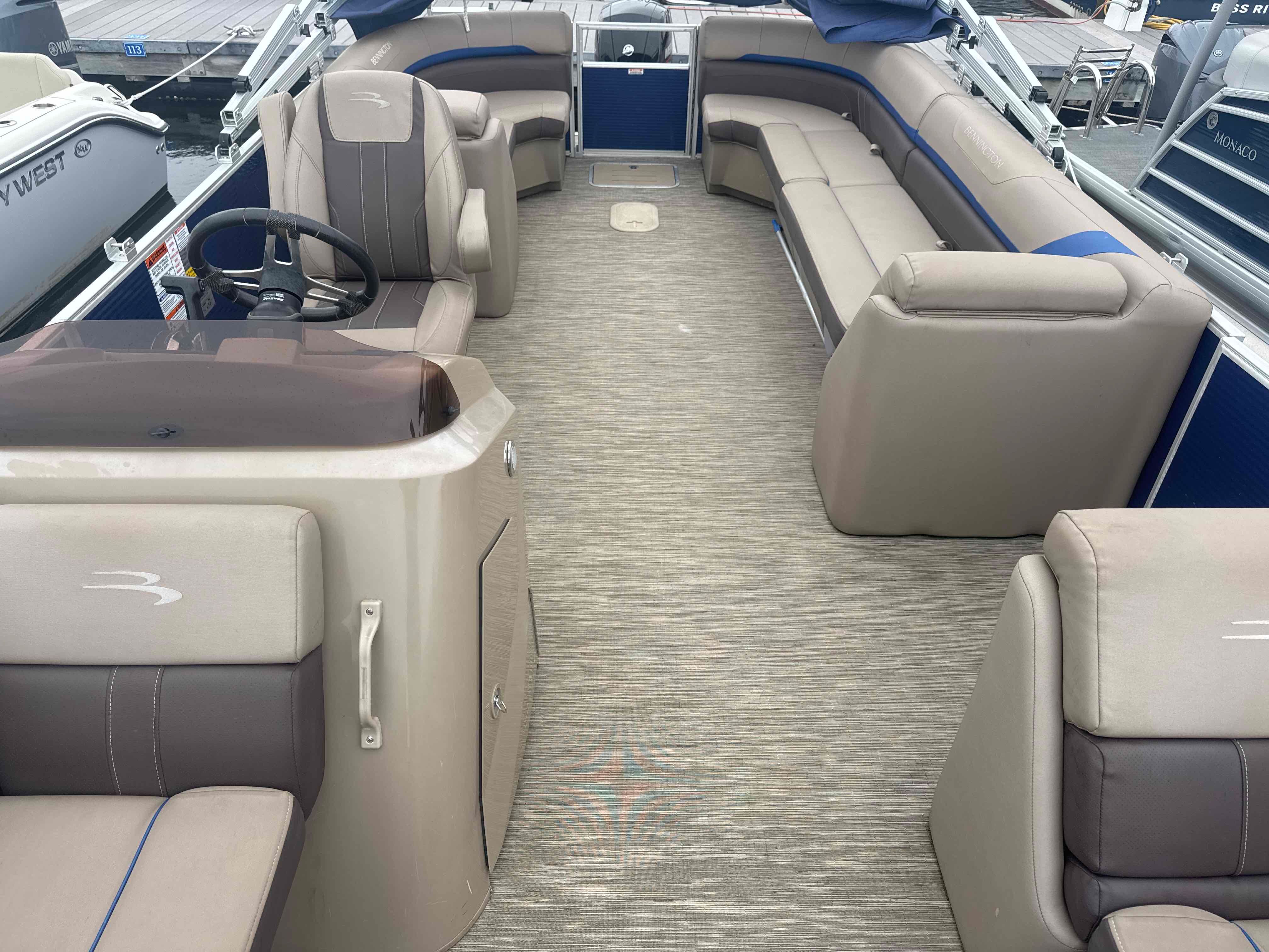 The image shows the interior of a 2023 Bennington 23SXSRC pontoon boat with beige seating.
