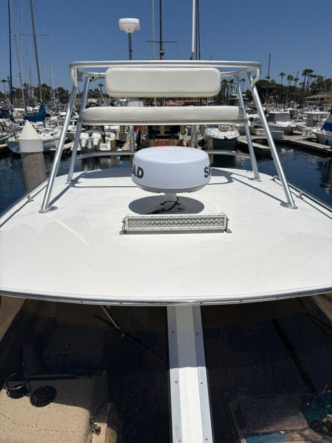 Boat with radar antennas and seating on the roof, docked in a marina.