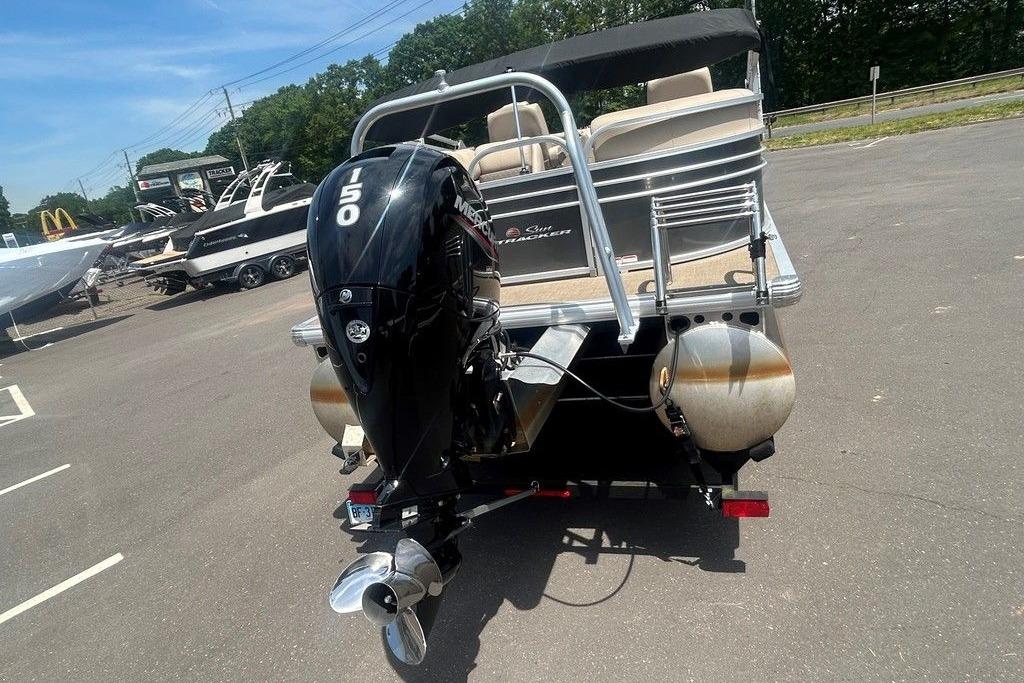 2023 Sun Tracker Party Barge 22 DLX with powerful outboard motor in parking lot.