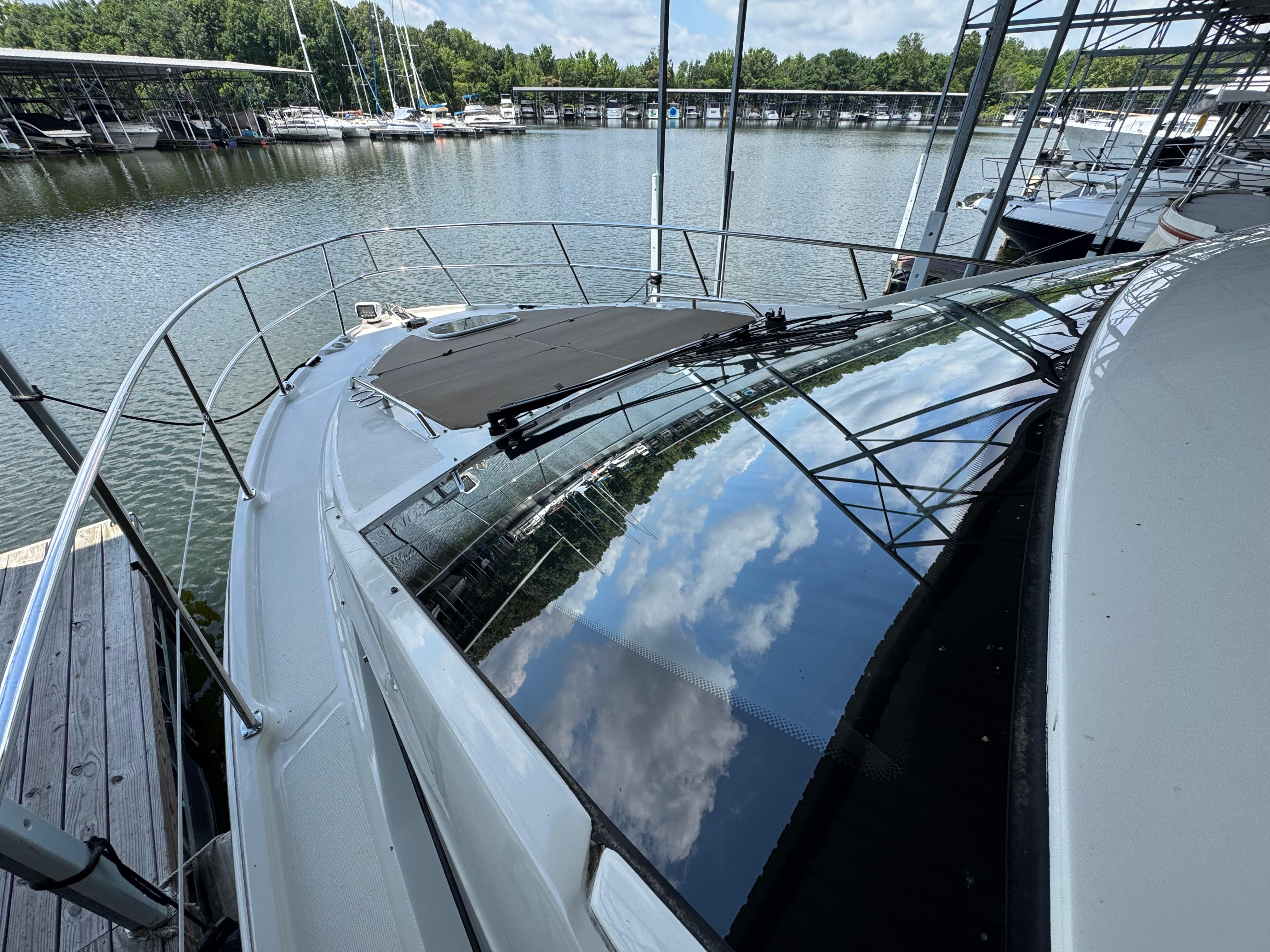2017 Sea Ray Sundancer 400 docked at marina, reflecting blue sky and clouds.