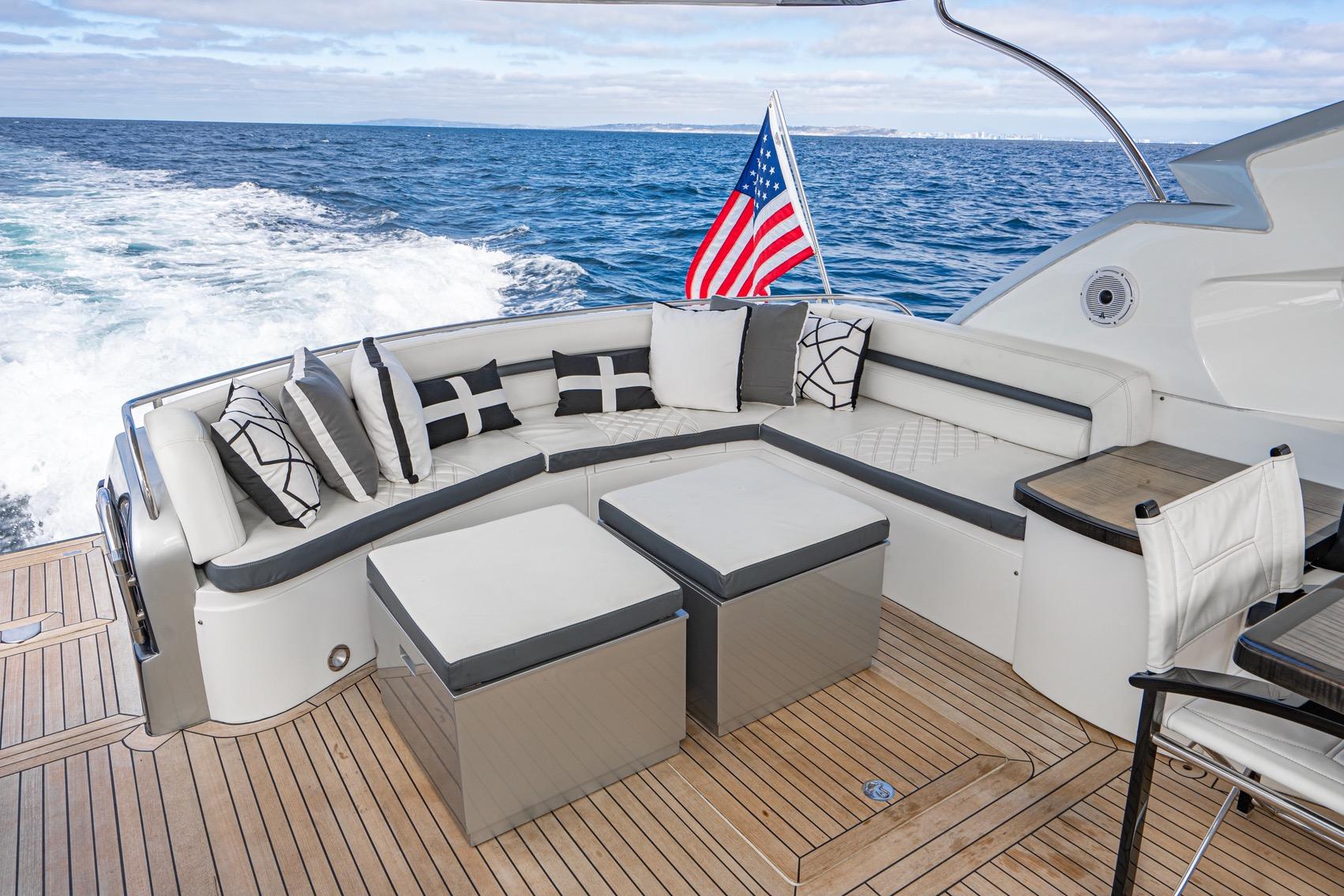 Luxurious Sunseeker Predator 68 yacht deck with elegant seating, ocean view, and American flag.
