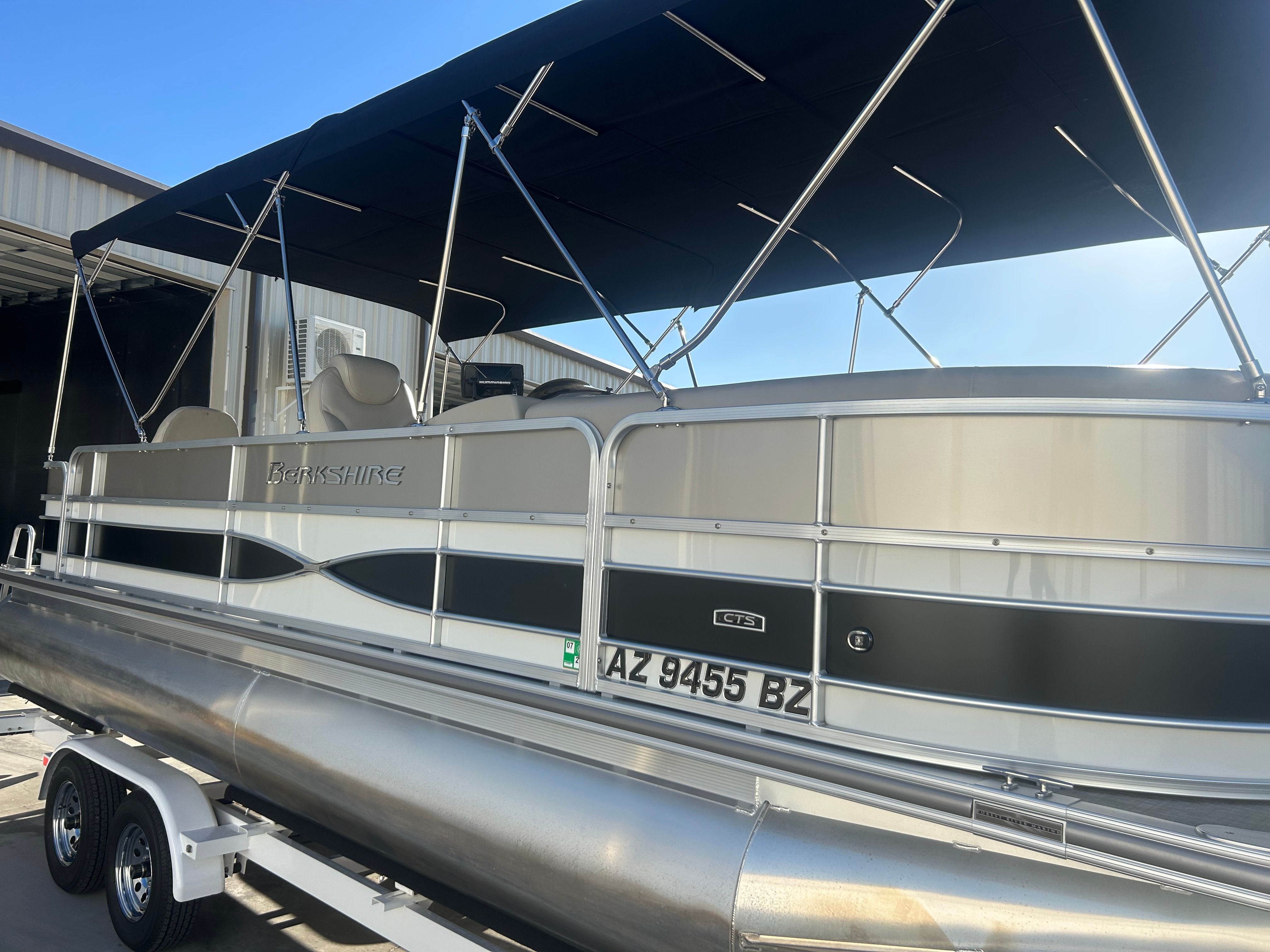 A 2018 Berkshire 24RFX CTS pontoon boat on a trailer, featuring a black canopy and silver hull.
