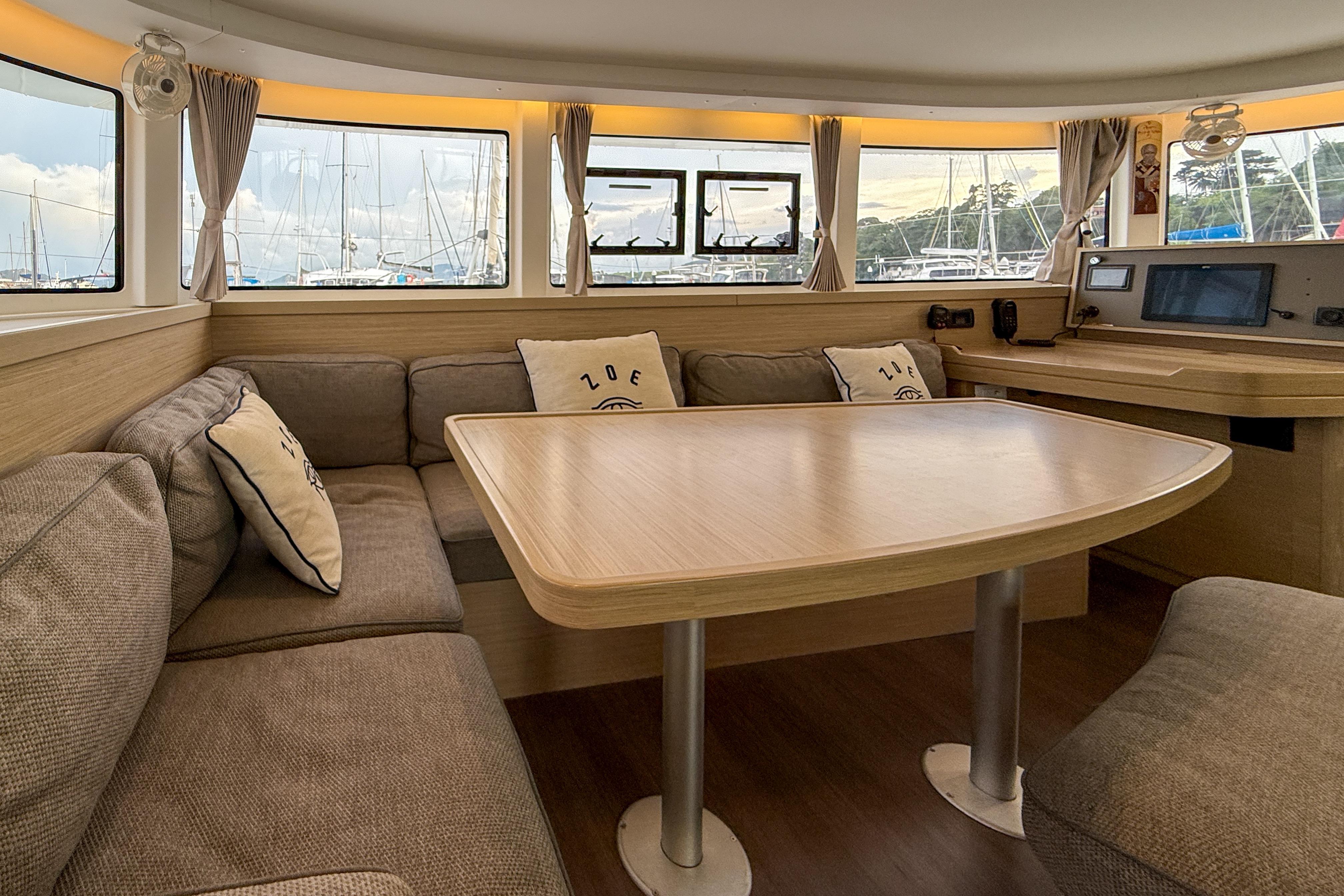 Interior of 2024 Lagoon 42 catamaran with cozy seating and large windows.