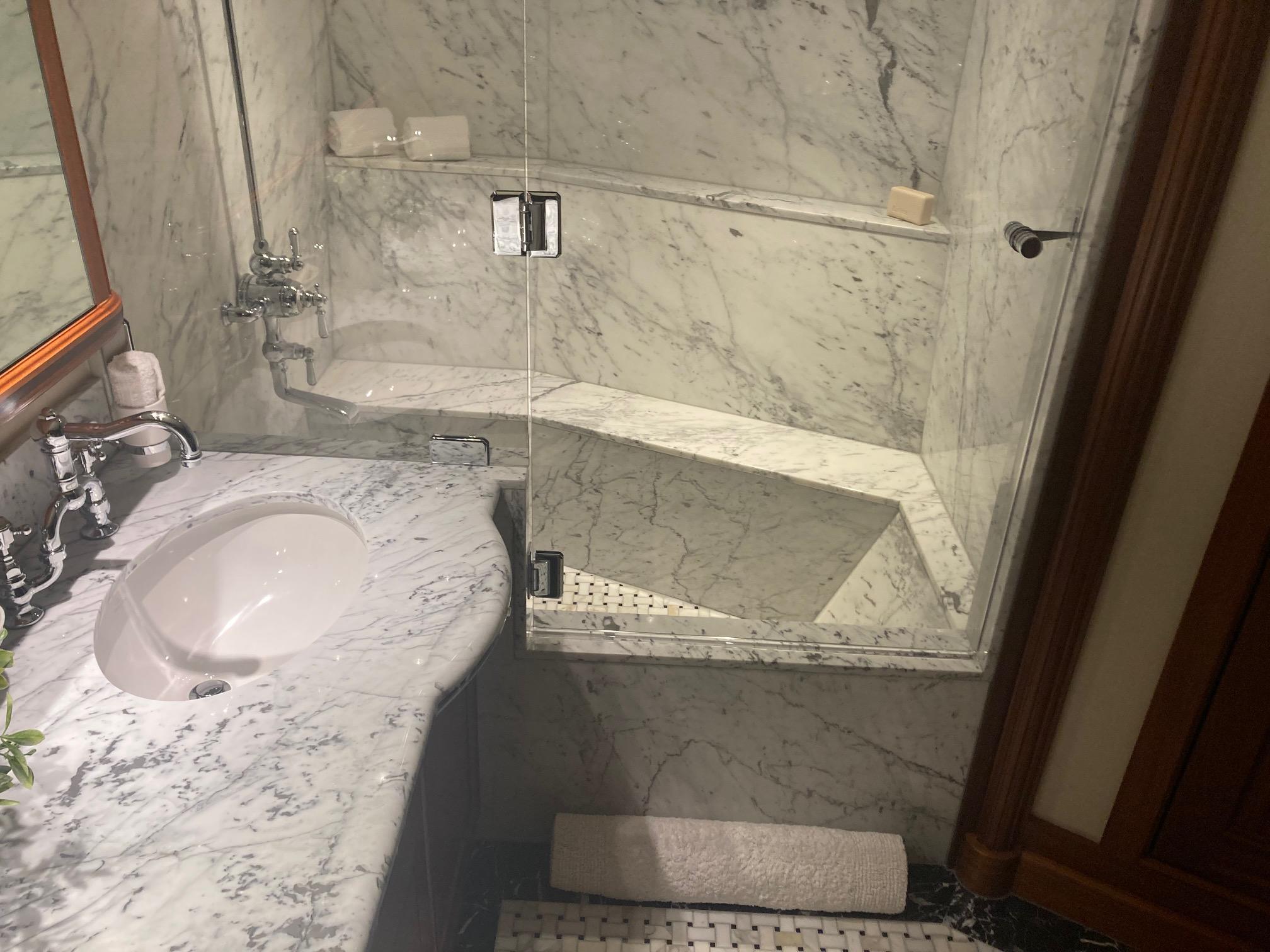 Luxurious marble bathroom in 2018 Allseas Expedition yacht, featuring elegant sink and glass shower.