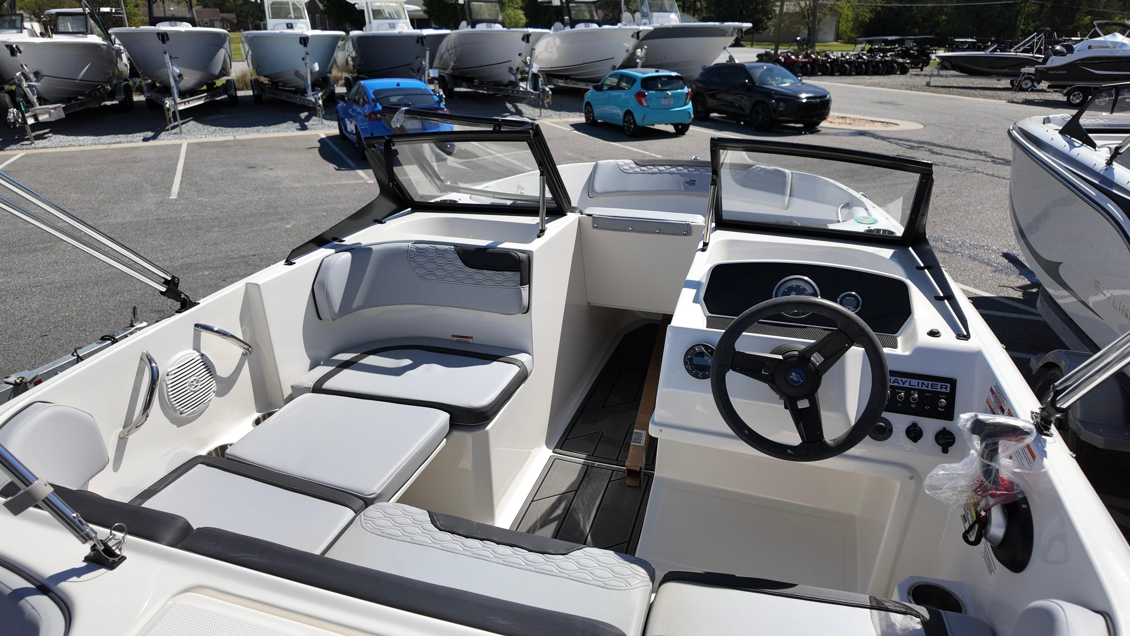 2025 Bayliner M17 boat interior with steering wheel and seating, parked in a marina.