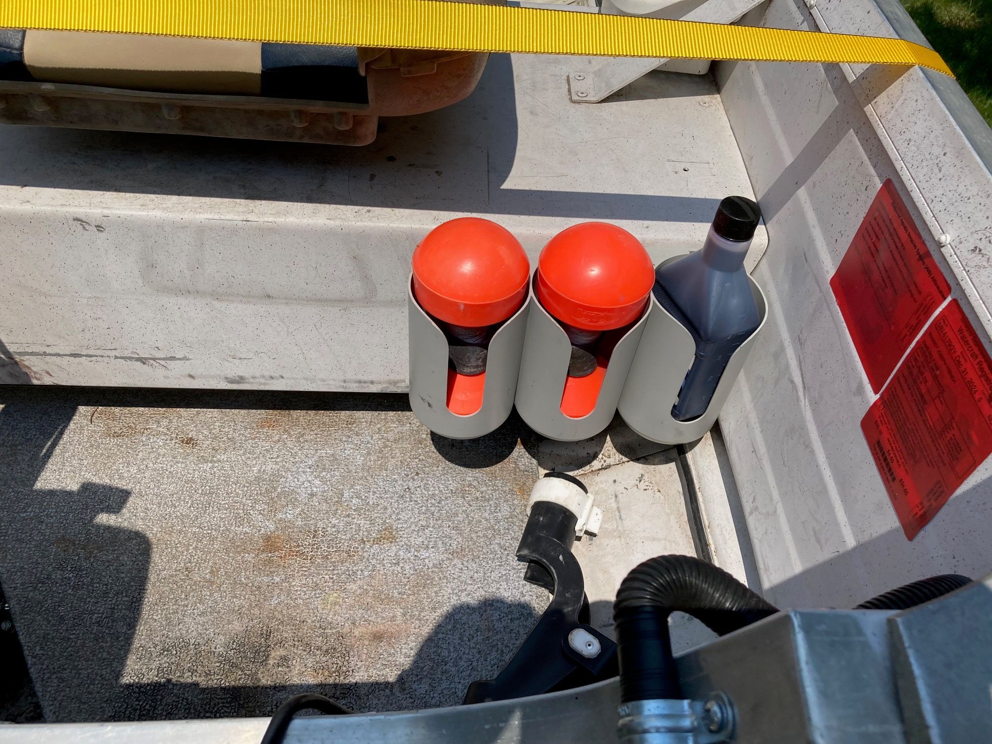 Three orange buoys and a bottle in a boat storage compartment.