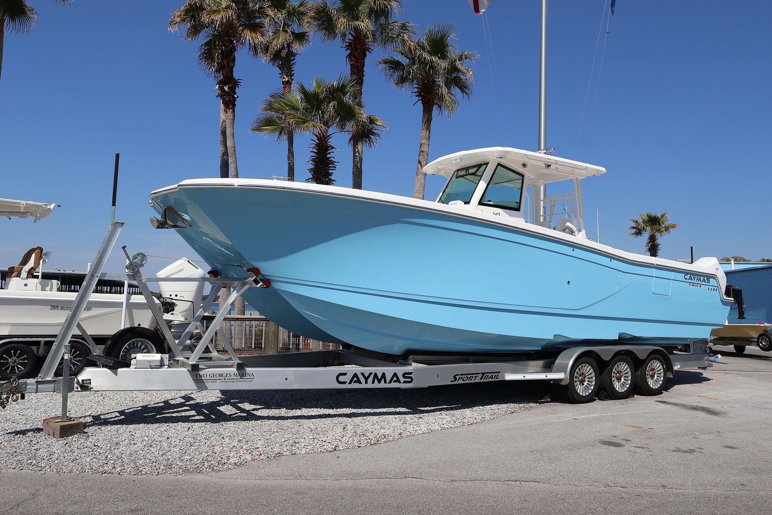 2026 Caymas 34 CT boat on trailer, parked under palm trees, clear blue sky.