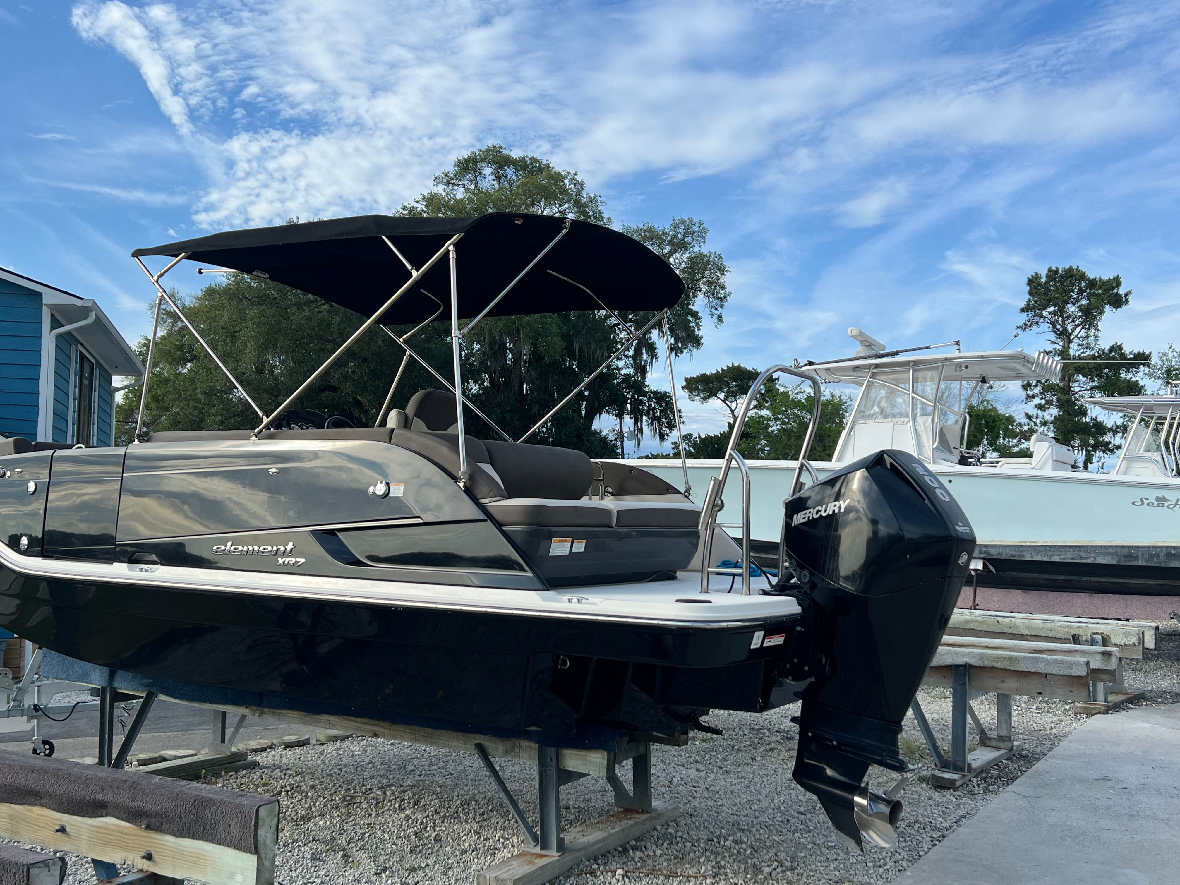 A 2019 Bayliner Element XR7 on a stand. It features a black canopy and an outboard motor.