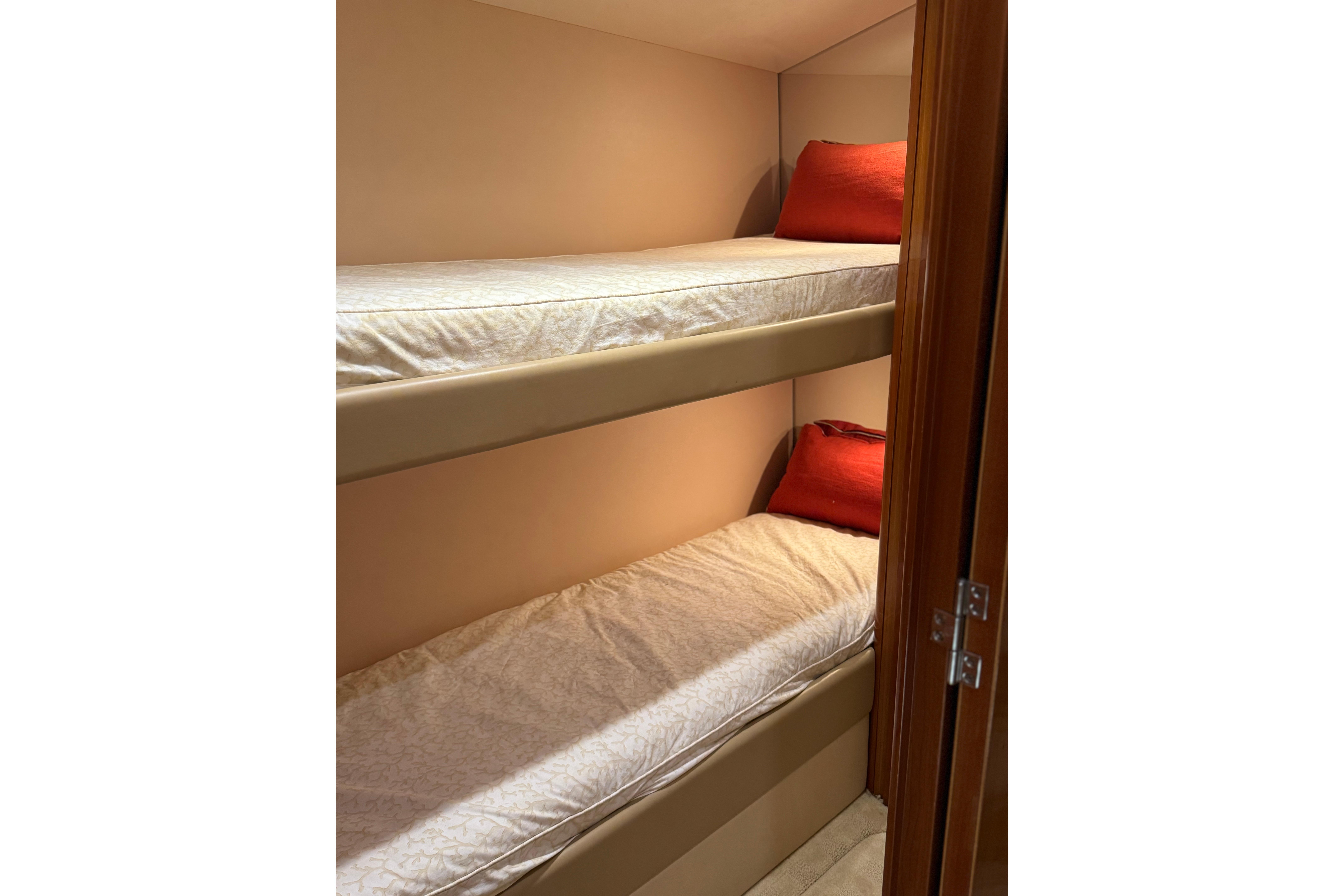 Bunk beds with red pillows in 2004 Hatteras 60 Convertible yacht cabin.