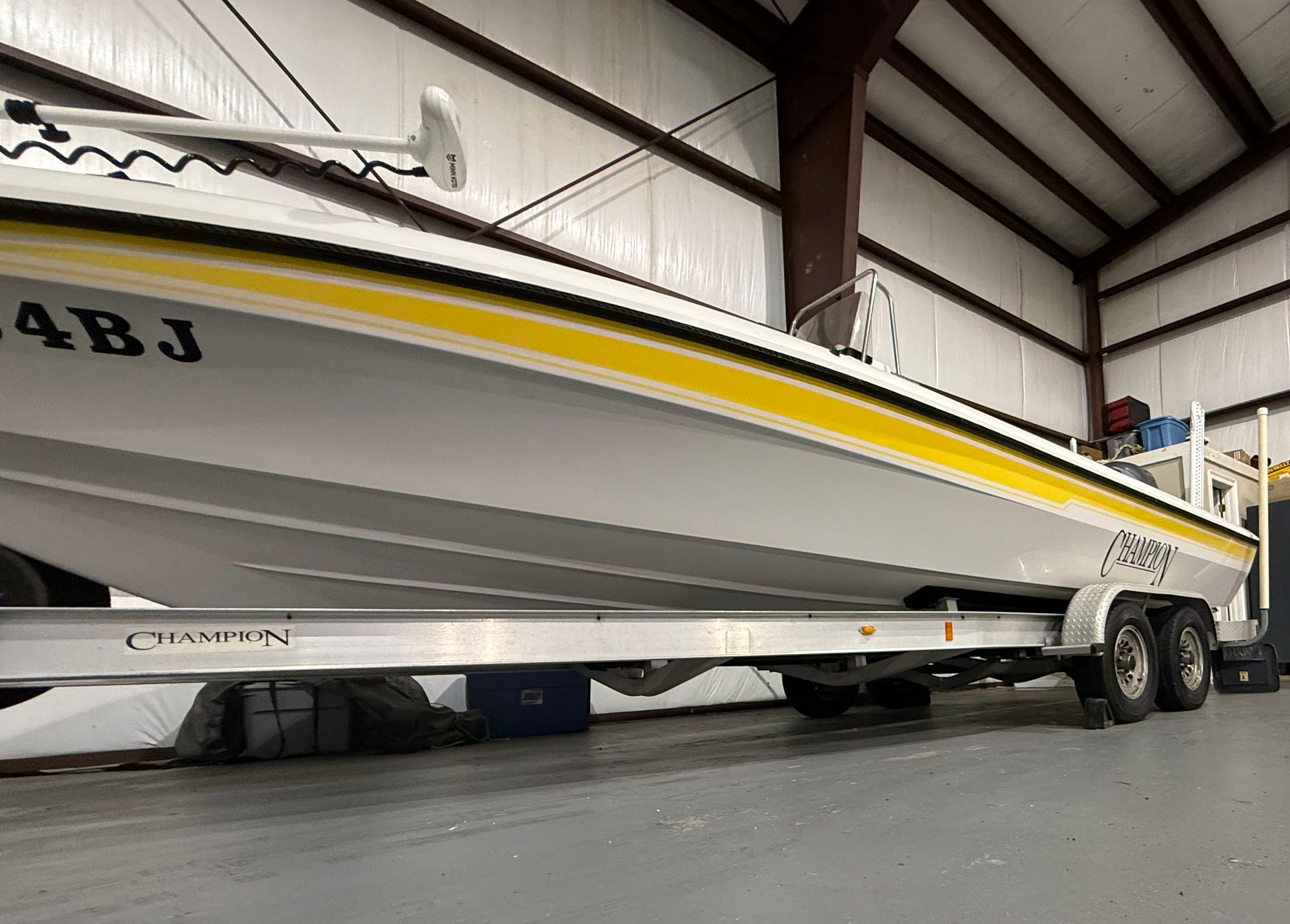 A 2004 Champion 24 Bay Champ boat on a trailer in a storage facility.