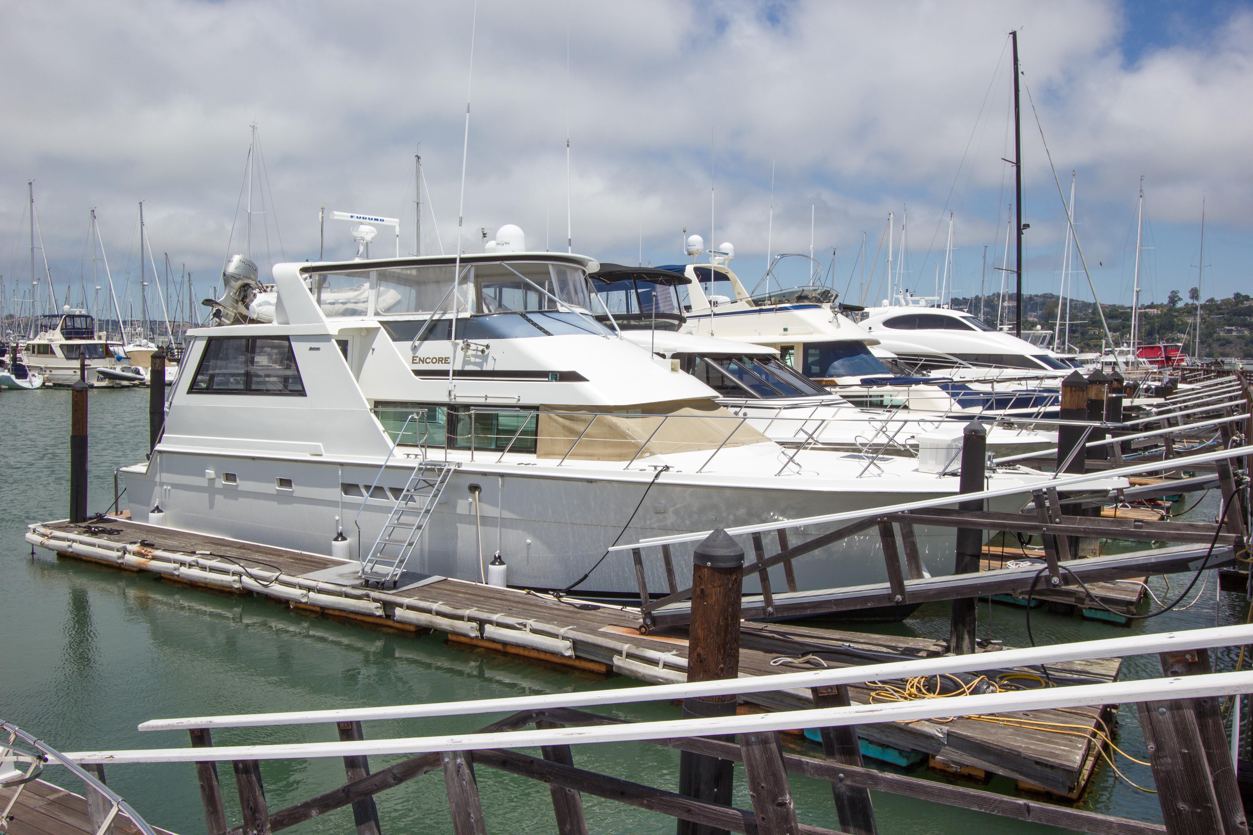 1994 Hatteras 52 Cockpit Motor Yacht docked at a marina under a cloudy sky.