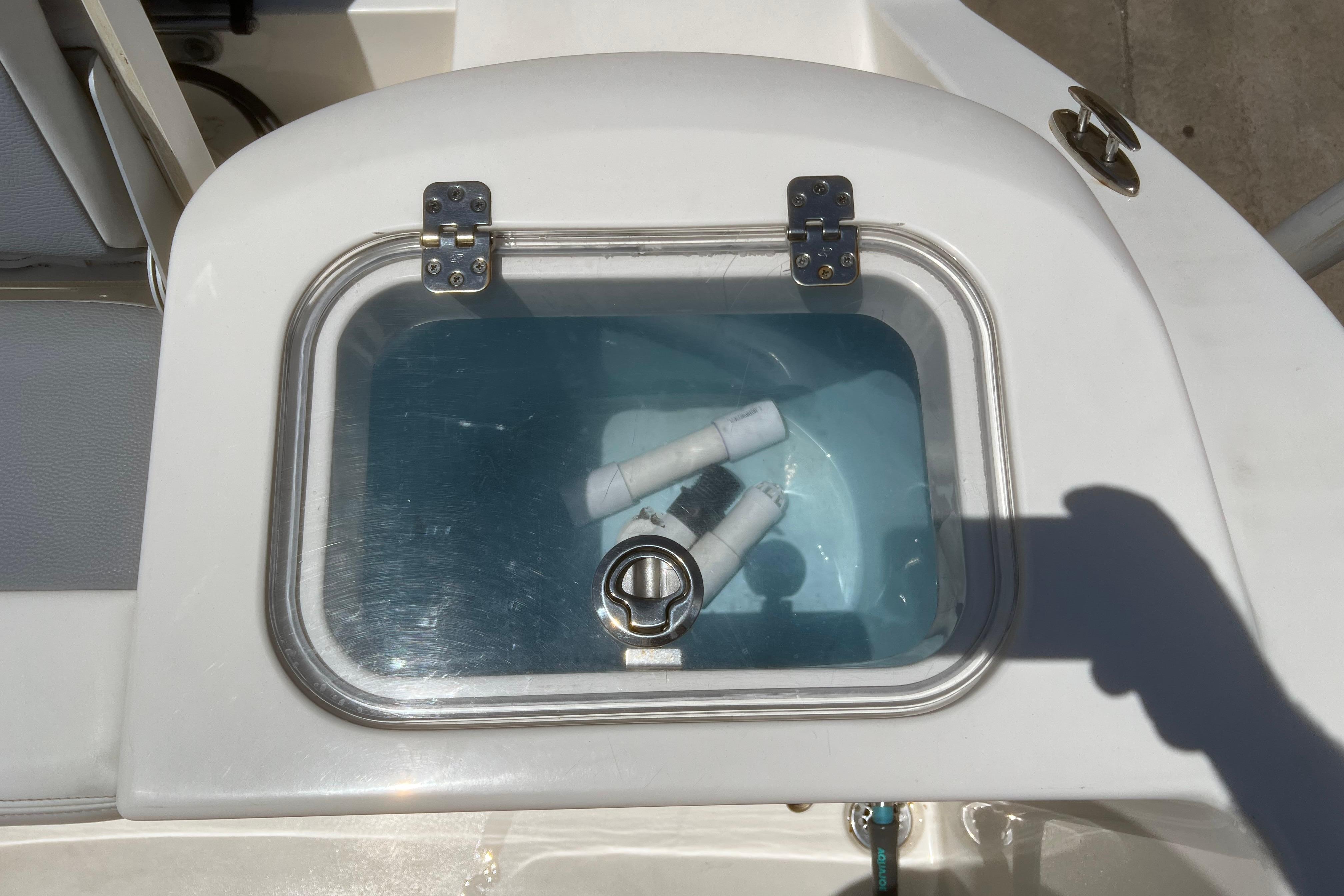 Livewell on 2018 Cobia 201 Center Console boat with clear lid and fittings inside.