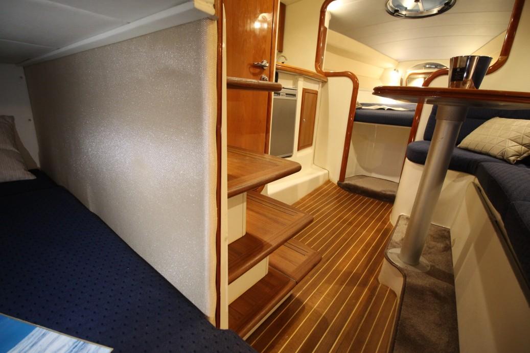 Interior of 2003 Airon Marine 325 yacht with wooden flooring and cozy seating area.