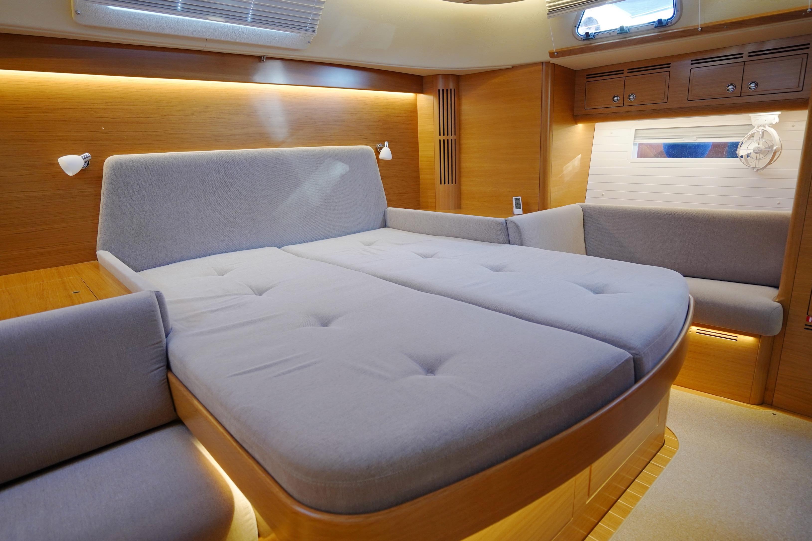 Luxurious interior of 2022 Hallberg-Rassy 57 yacht with spacious bed and elegant wood finish.