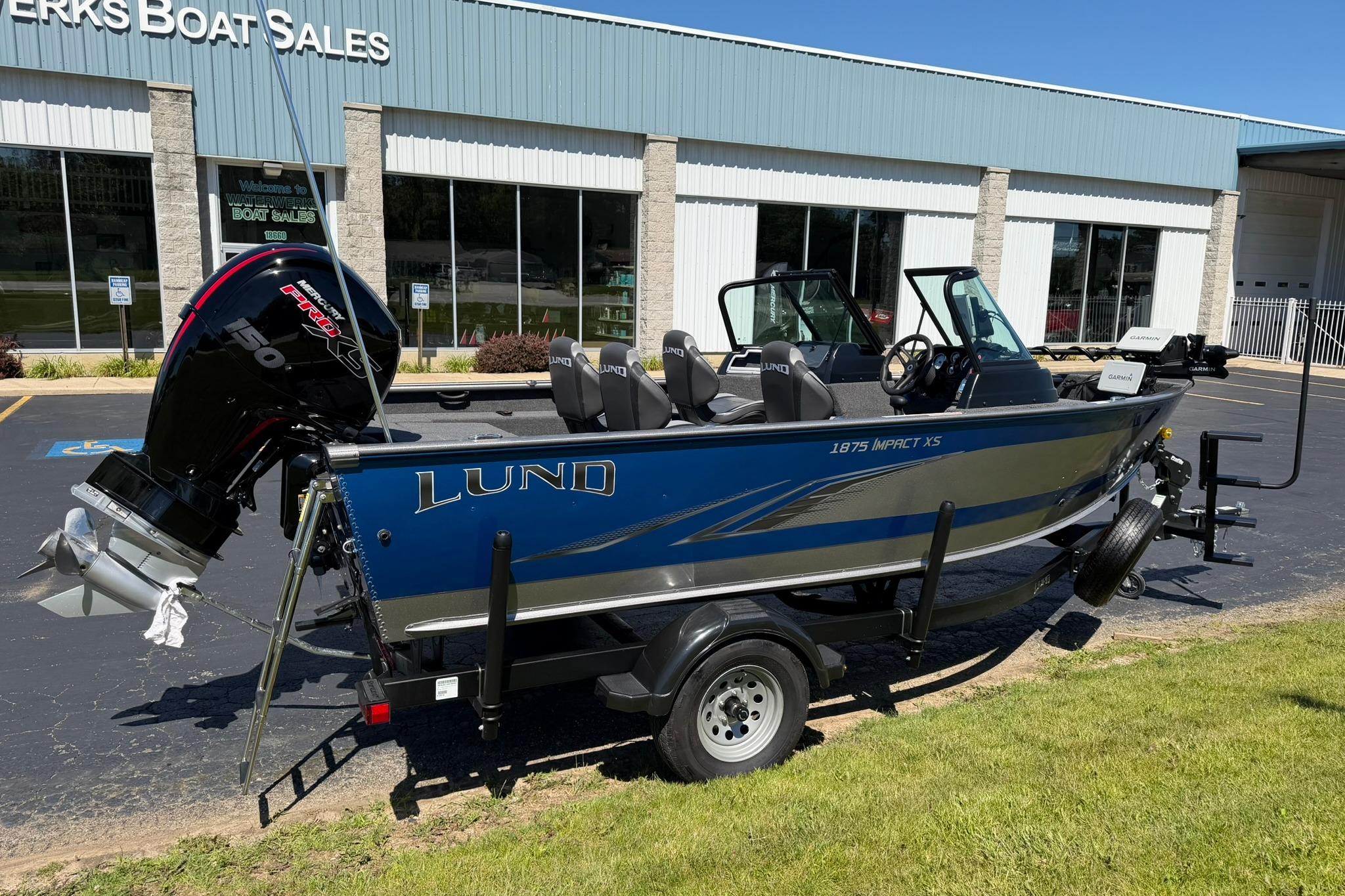 2024 Lund 1875 Impact XS Sport boat on trailer outside dealership.