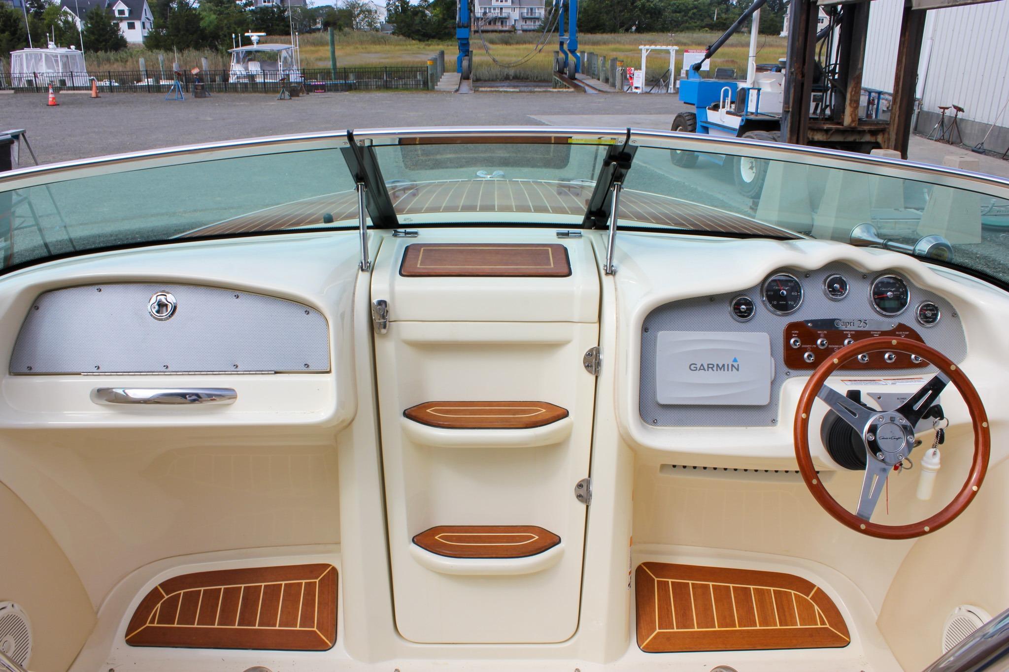 2017 Chris-Craft Capri 27 boat dashboard with Garmin navigation and wooden steering wheel.