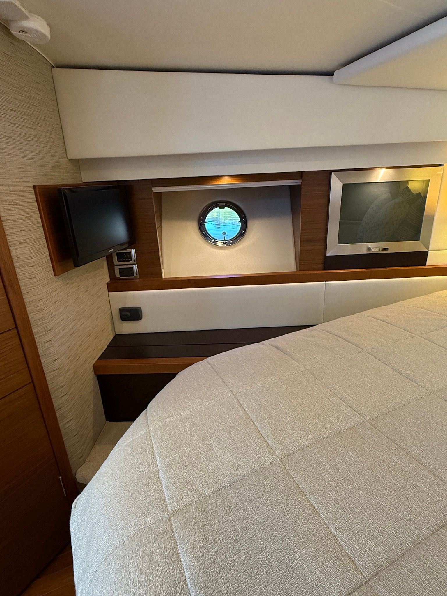 Interior of Tiara Yachts C44 Coupe with bed, porthole, and TV.