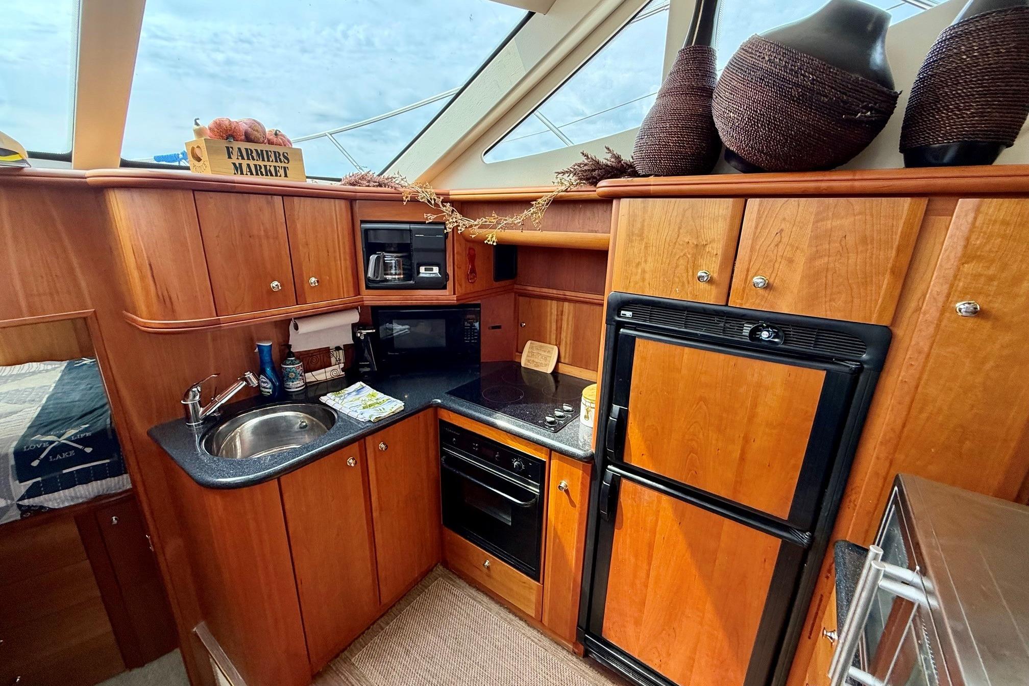 Luxurious 2004 Silverton 39 Motor Yacht kitchen with wood cabinetry and modern appliances.
