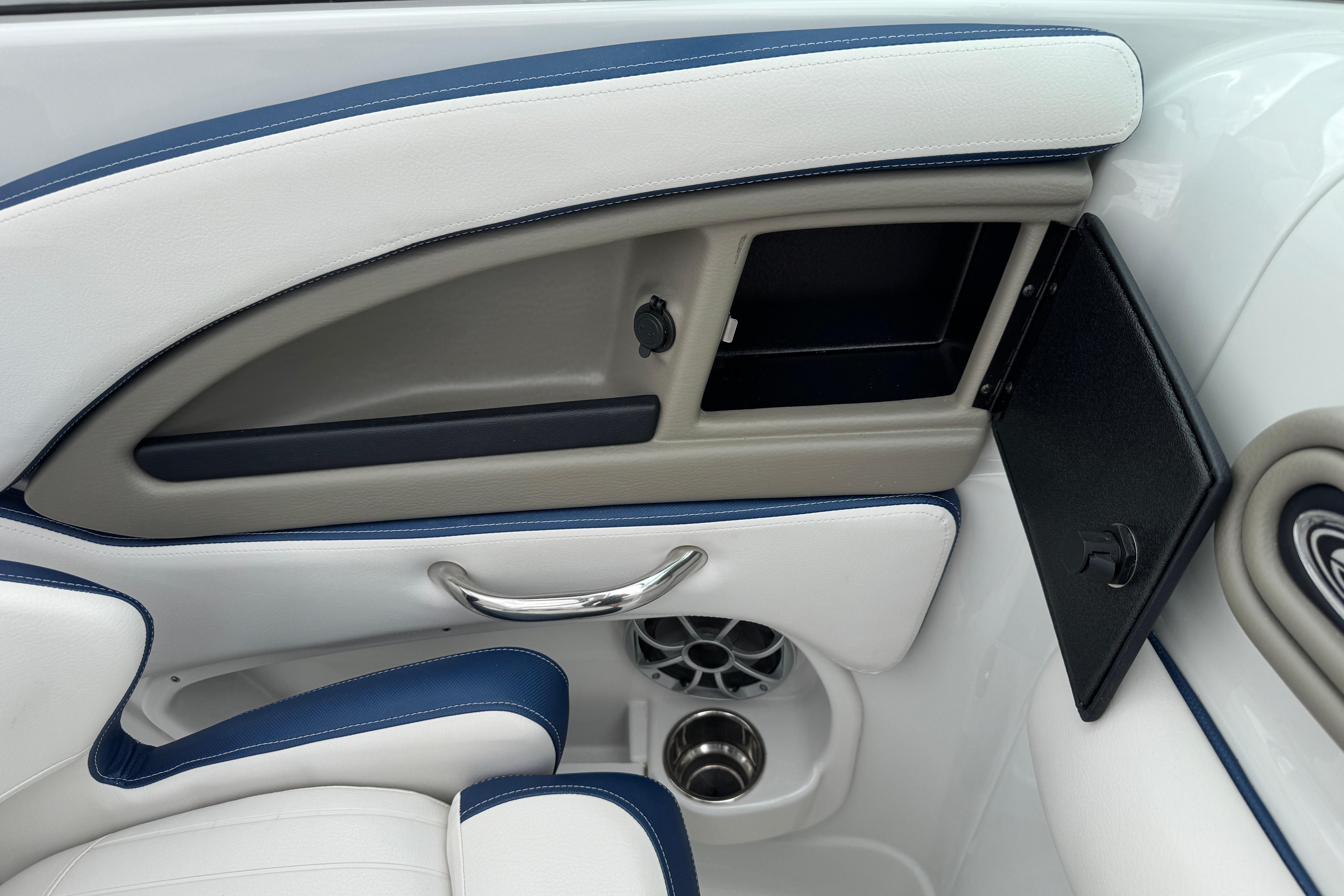 Interior detail of 2025 Crownline 290 XSS boat, featuring storage compartment and cup holders.