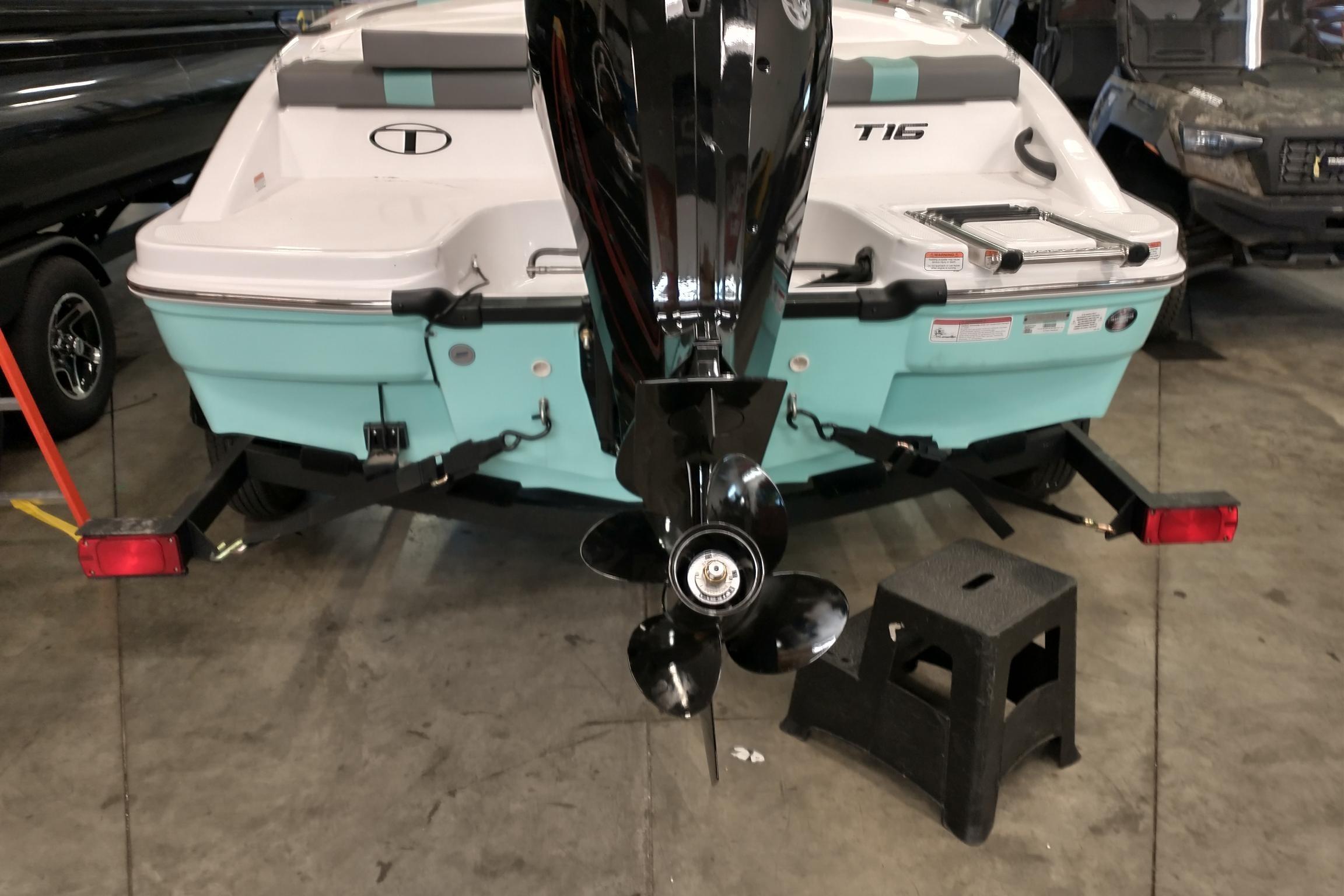 Rear view of 2026 Tahoe T16 boat with outboard motor in a garage.