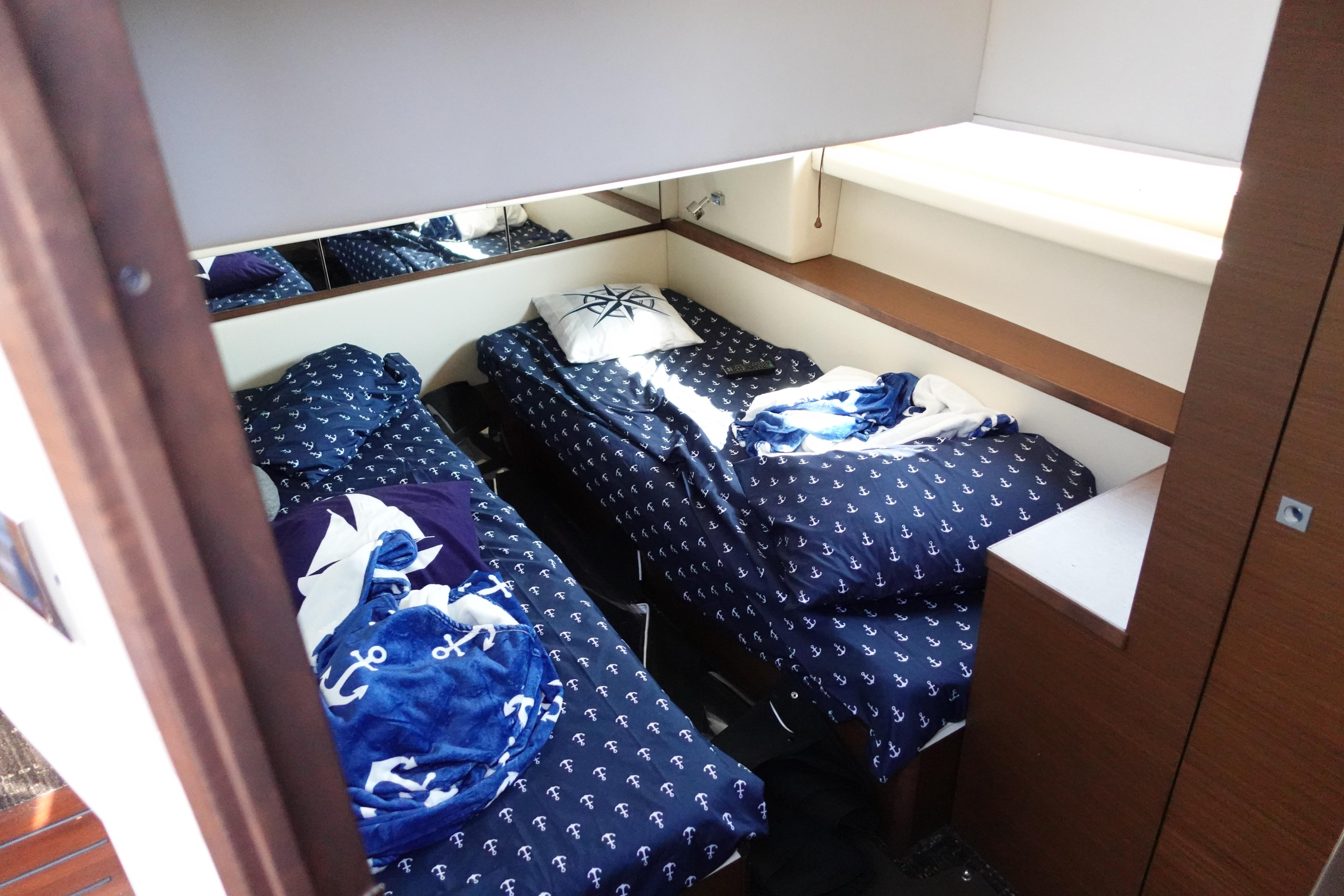 Cabin interior of 2012 Sea Ray 450 Sedan Bridge with twin beds and nautical-themed bedding.