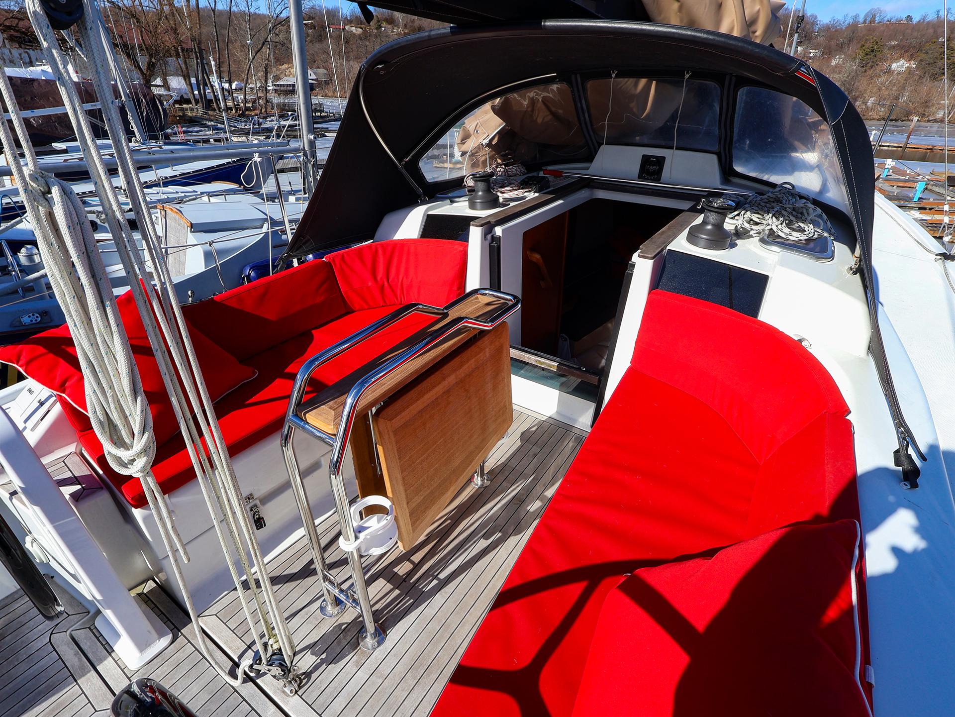 2018 Hanse 315 yacht cockpit with red seating and wooden table.