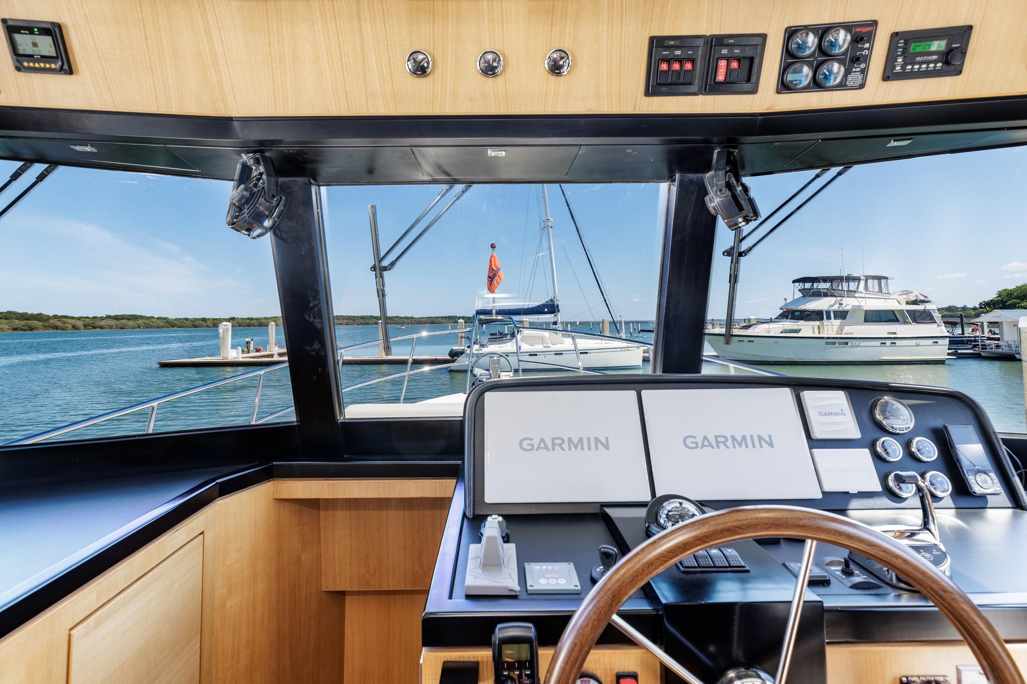 Helm of 2023 North Pacific 49 Euro yacht with Garmin navigation, docked at marina.