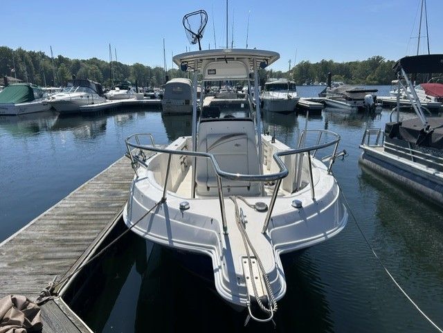 A 2000 Aquasport Osprey 250 docked at a marina, surrounded by other boats.