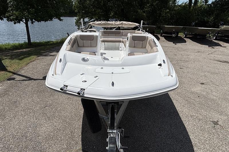 2026 Tahoe 2150 boat on trailer by a lakeside, showcasing sleek design and spacious seating.