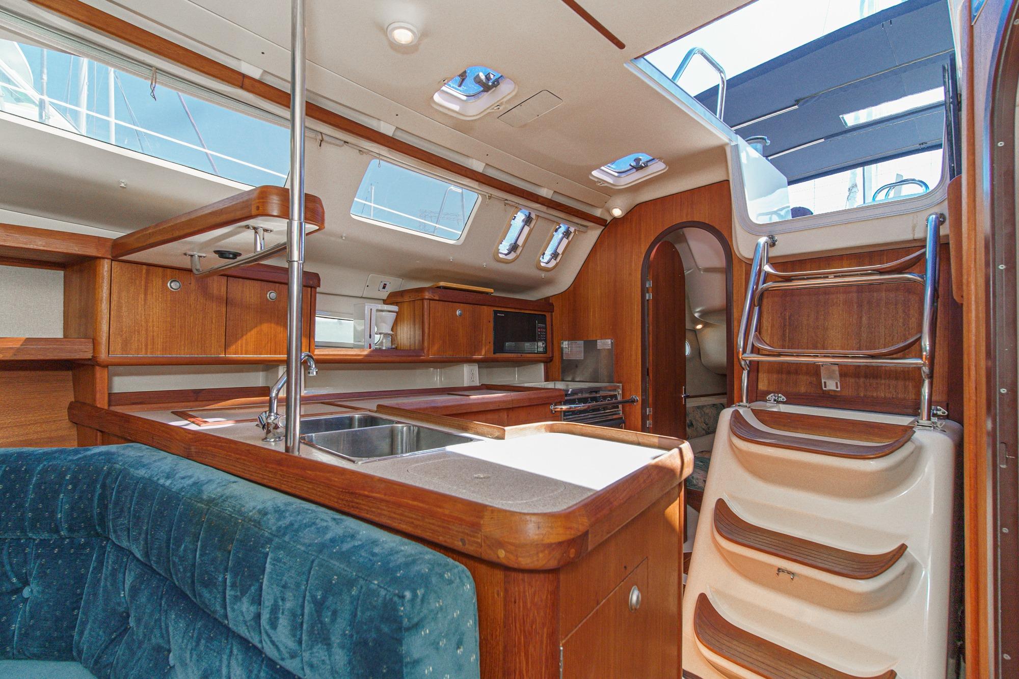Interior of a 1996 Hunter 376 sailboat with wooden cabinetry and blue seating.