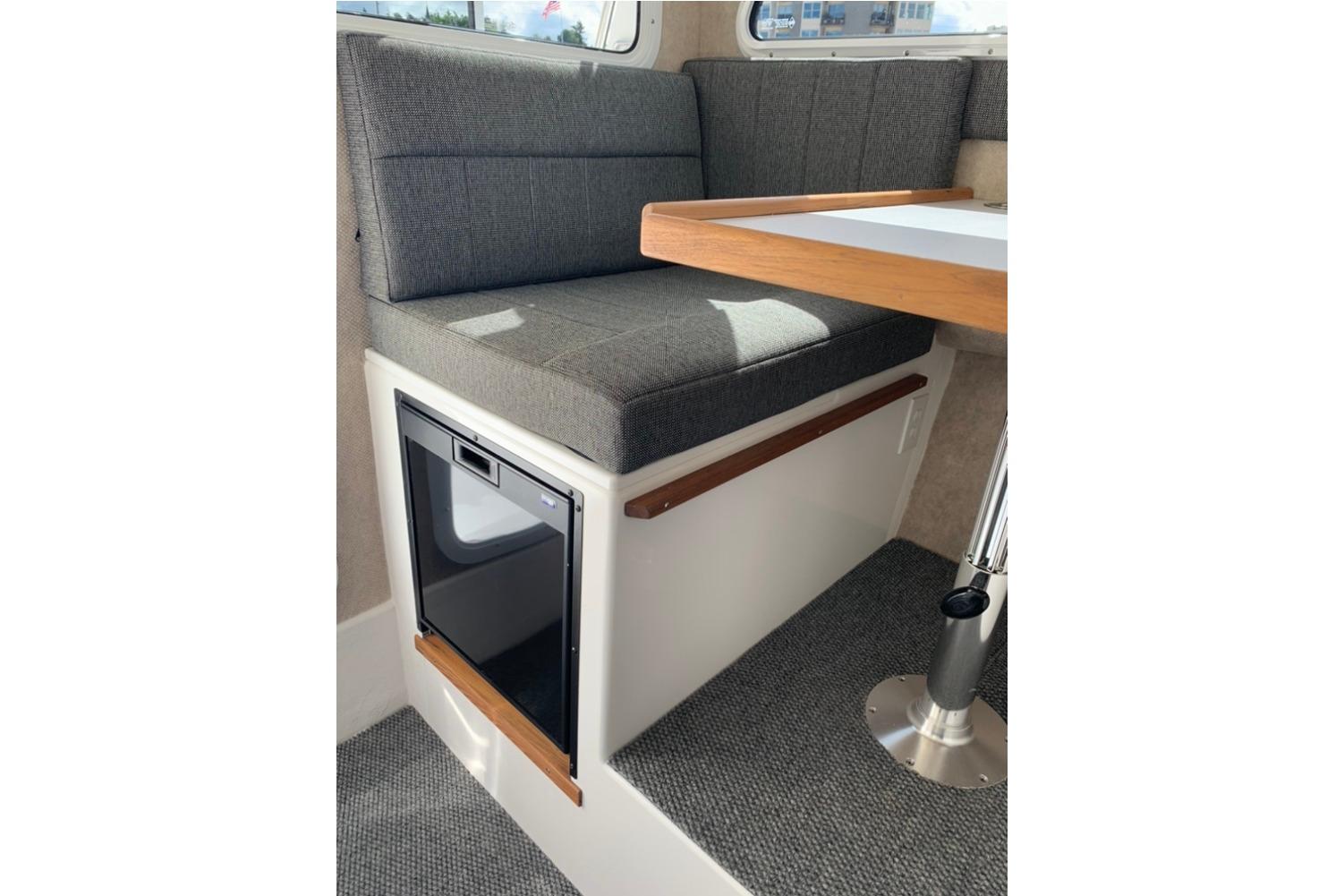 Interior of 2026 Sea Sport Kenai 2600, featuring a cushioned seating area and table.