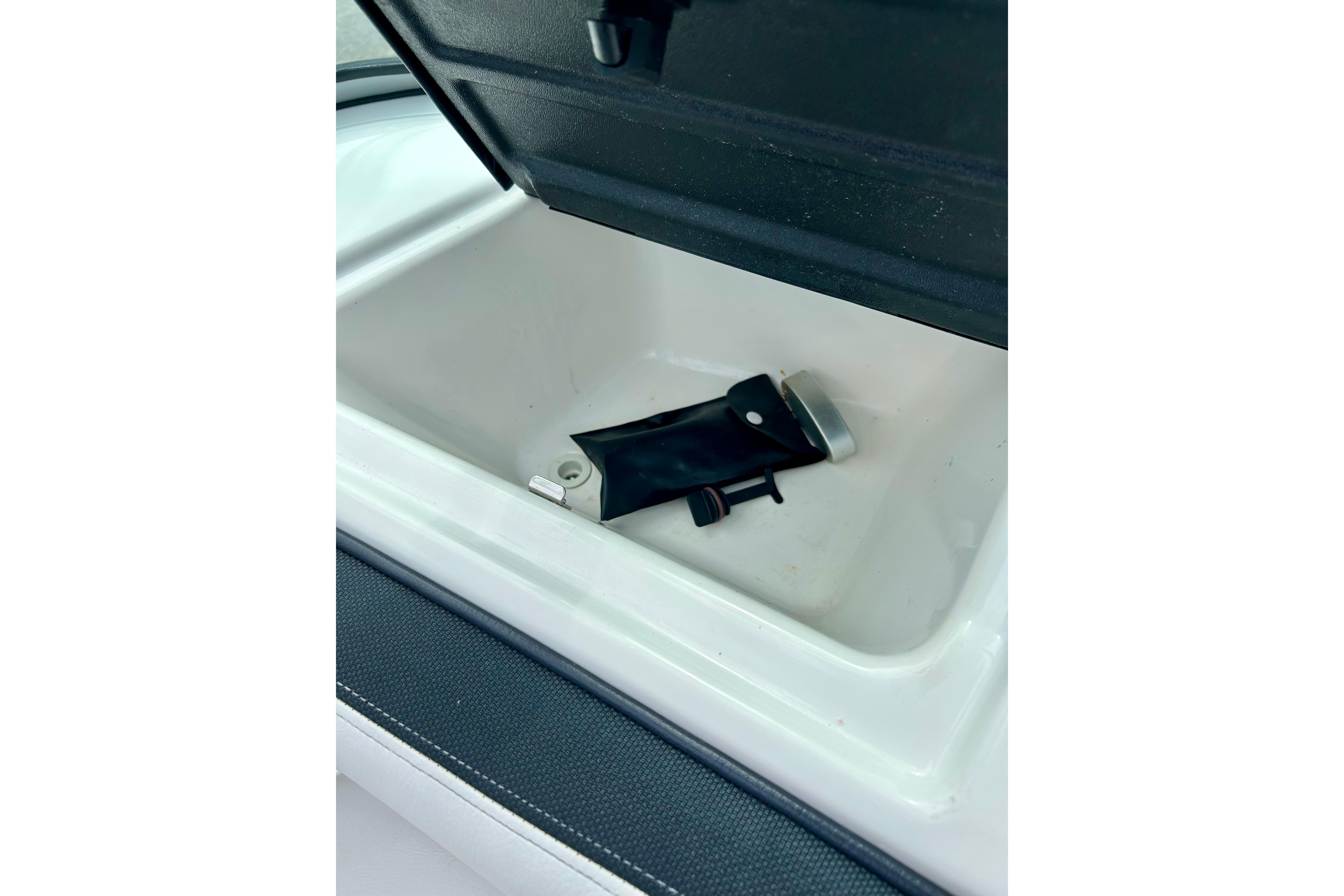 Open storage compartment in a 2015 Yamaha AR210 boat, featuring a black accessory inside.