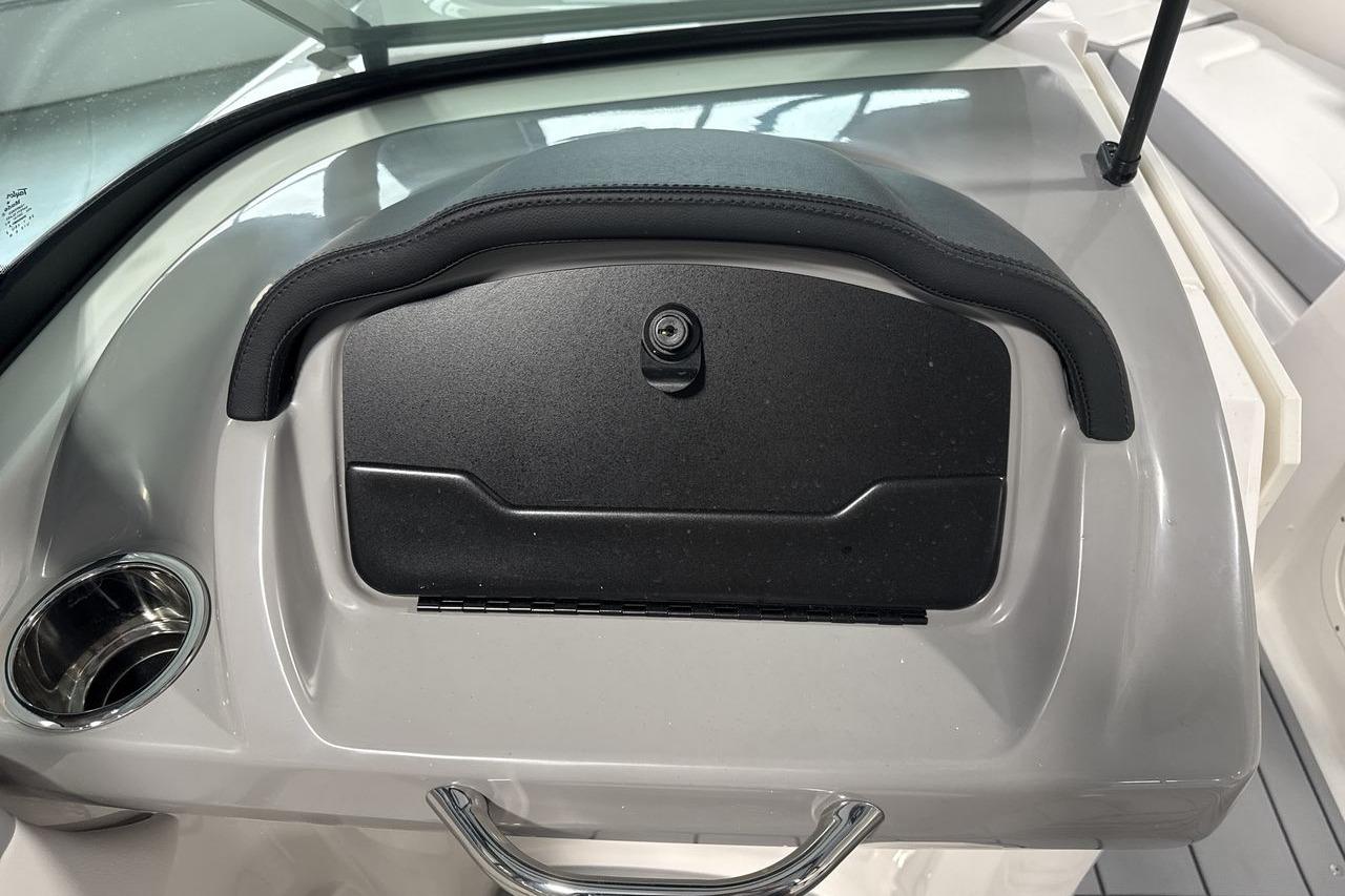 The image shows a gray dashboard with a closed compartment and a cup holder.