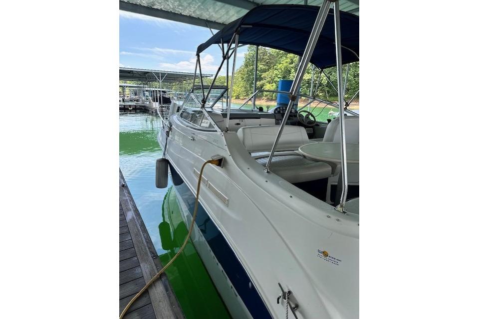 2003 Bayliner 2655 Ciera docked under a canopy, with visible seating and steering wheel.