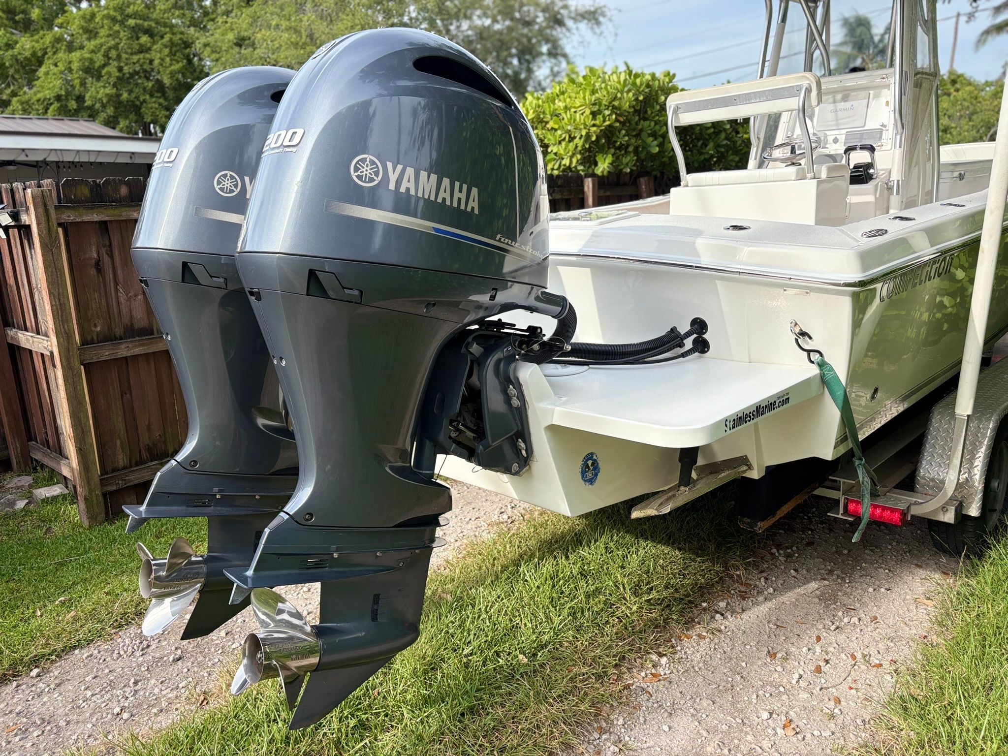 A boat with two Yamaha outboard motors is on a trailer outdoors.
